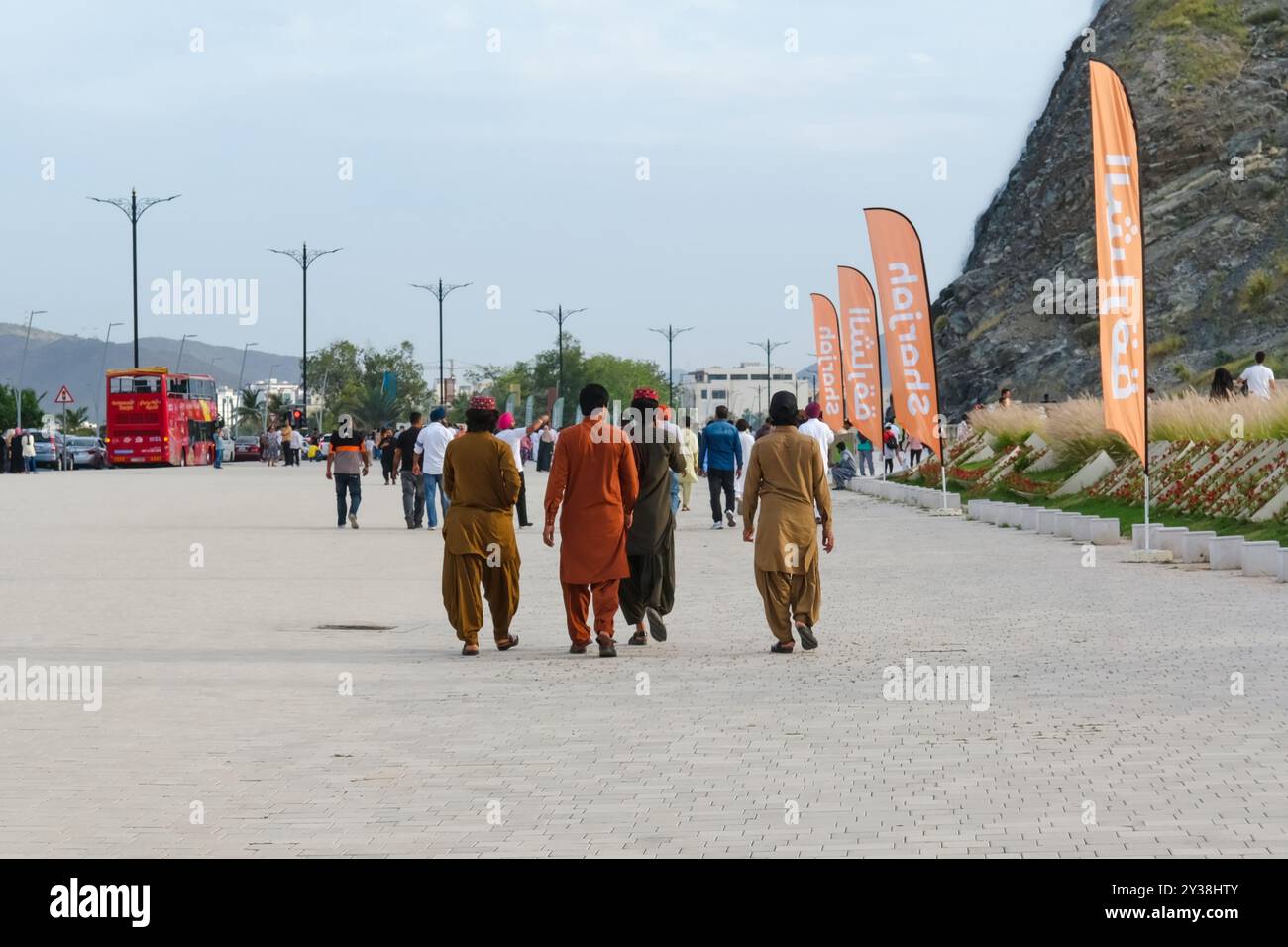 Vue arrière du groupe de 4 jeunes hommes migrants pauvres du moyen-Orient portant un tissu décontracté traditionnel coloré marchant dans les rues pour les vacances de l'Aïd Al Fitr Banque D'Images