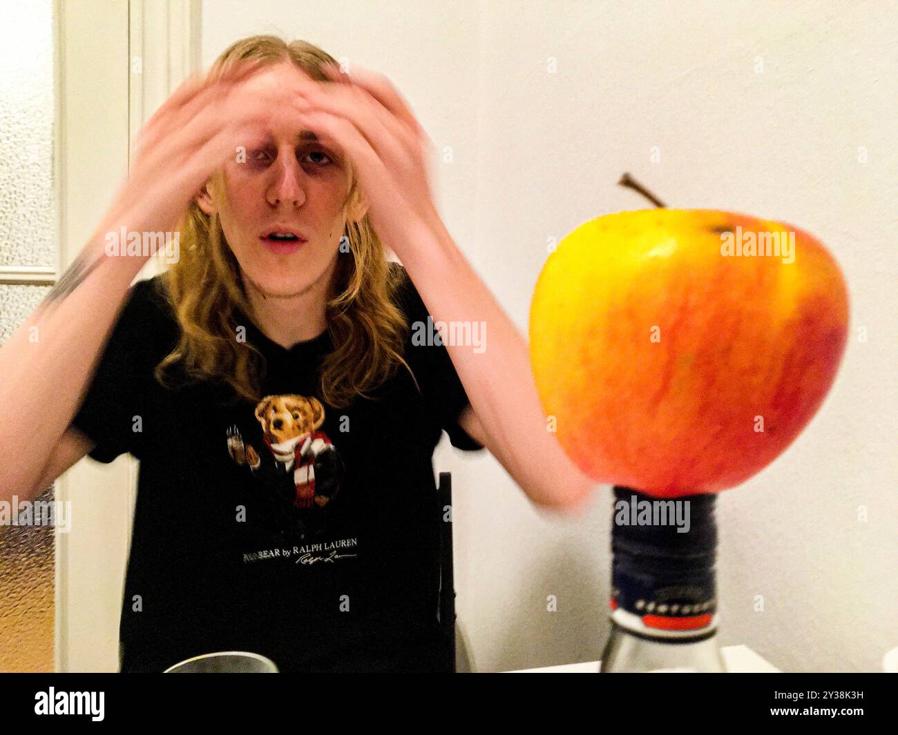 Homme et Apple jeune homme et une pomme à sa table de cuisine. Berlin, Allemagne. MRYES Berlin Koppenstasse Berlin Allemagne Copyright : xGuidoxKoppesxPhotox Banque D'Images