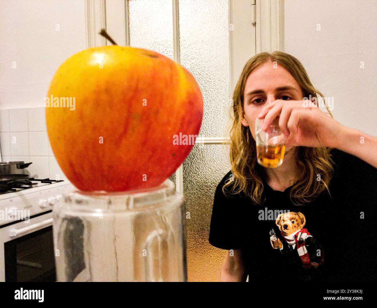 Homme et Apple jeune homme et une pomme à sa table de cuisine. Berlin, Allemagne. MRYES Berlin Koppenstasse Berlin Allemagne Copyright : xGuidoxKoppesxPhotox Banque D'Images