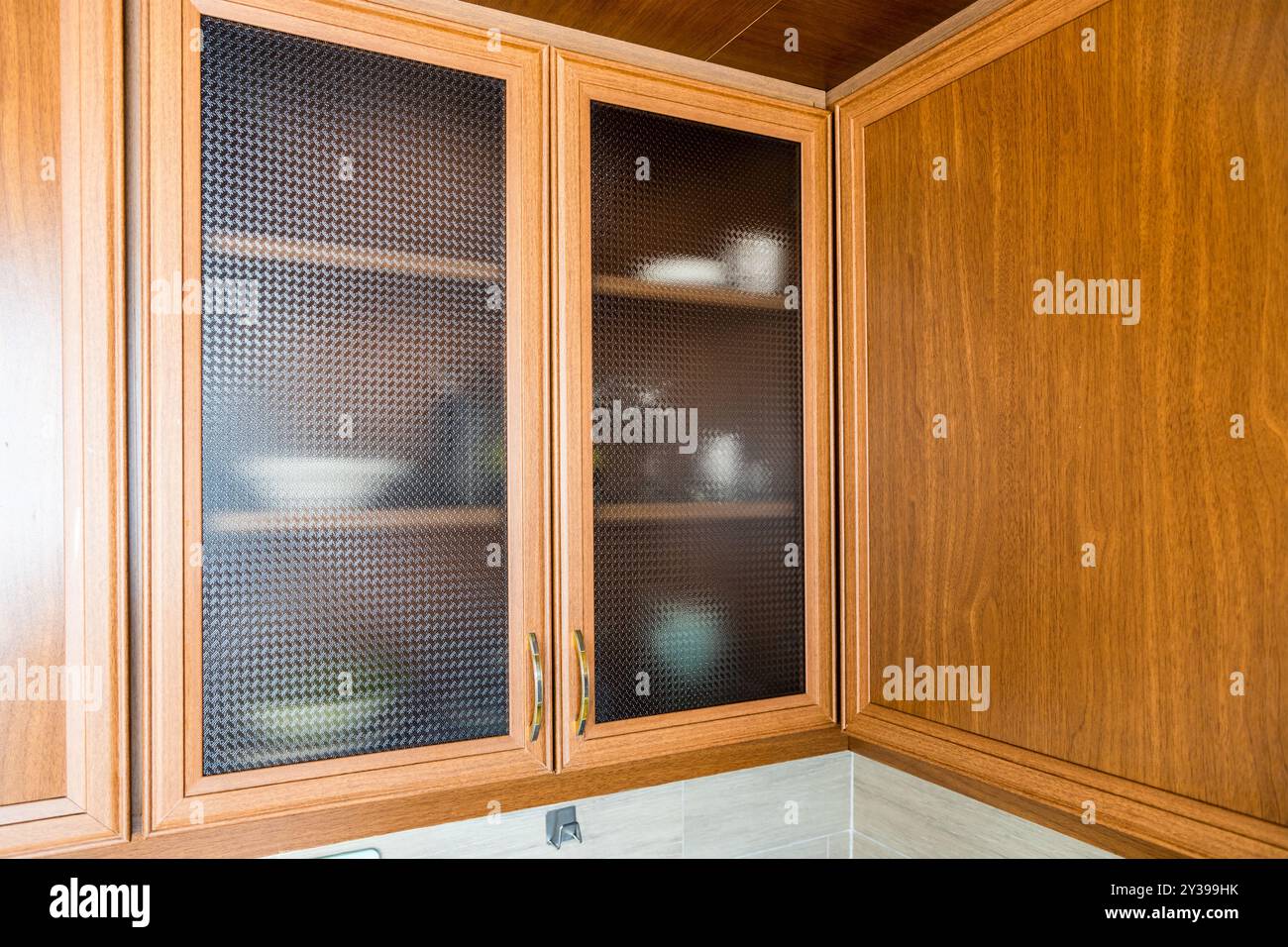 portes d'armoire murale à cadre en bois avec verre nervuré dans la cuisine à la maison Banque D'Images