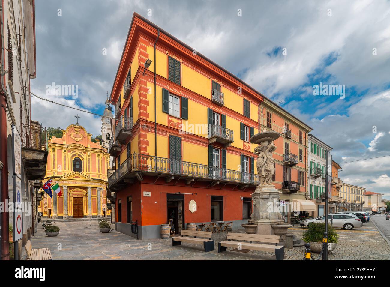 Caraglio, Italie - 06 septembre 2024 : vue sur la via Roma avec de vieux bâtiments décorés et la fontaine des trois grâces, en arrière-plan la paroisse Banque D'Images