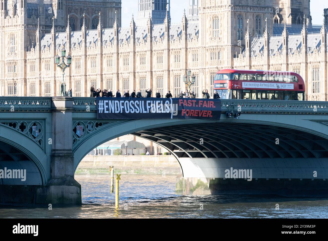 Londres, Royaume-Uni. 13 septembre 2024. Une grande bannière déclarant « mettre fin aux combustibles fossiles » est lâchée sur le pont de Westminster, par les chambres du Parlement, marquant le lancement de ce que les organisateurs prétendent être la plus grande action mondiale jamais entreprise pour exiger que les gouvernements travaillent pour mettre fin à l'utilisation des combustibles fossiles. La semaine d’action, du 13 au 20 septembre, voit la campagne Global Fight to End Fossil Fuels unir ses forces à la campagne Pay Up for Climate Finance pour exiger une élimination juste et équitable des combustibles fossiles comme moyen nécessaire pour lutter contre les menaces du chauffage mondial. Crédit : Ron Fassbender/Alamy Live News Banque D'Images