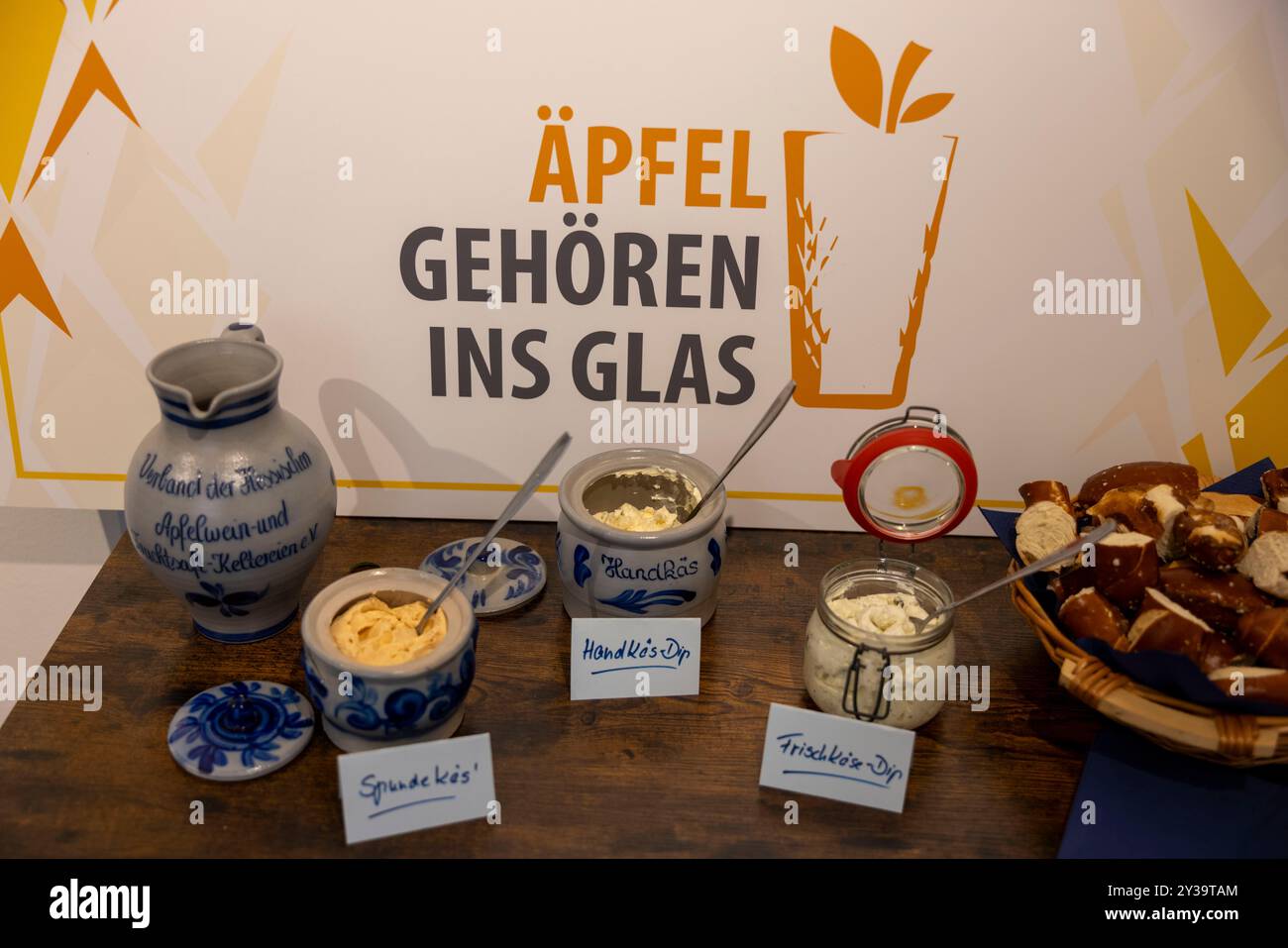 Hanau, Allemagne. 13 septembre 2024. Un Bembel traditionnel (l), un pichet en grès pour le cidre et des pâtes à tartiner de style Hesse, y compris le Spundekäs, sont présentés sur un buffet. Les producteurs de cidre ouvrent la saison 2024 sous la devise « les pommes appartiennent à un verre ». Crédit : Helmut Fricke/dpa/Alamy Live News Banque D'Images