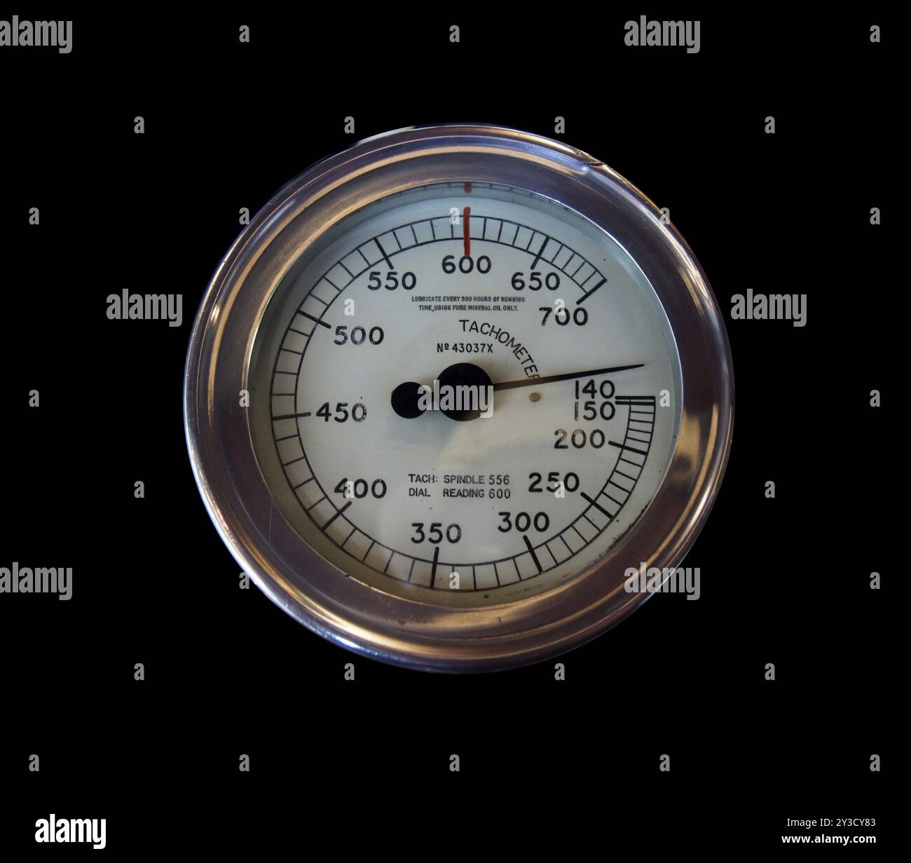 Un vieux tachymètre industriel rond en métal sur fond noir avec des chiffres marqués sur un cadran blanc Banque D'Images