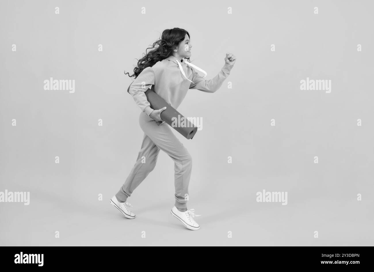 Courez et sautez. Adolescente vêtue d'un uniforme sportif, posant dans le studio. Enfant dans un élégant costume de sport chic dans un sweat à capuche avec capuche. Publicité Banque D'Images