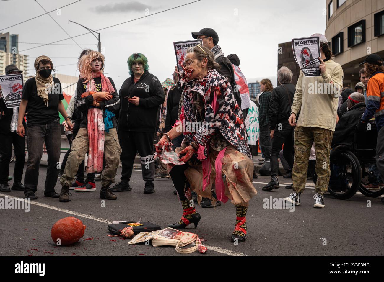 Melbourne, Australie. 13 septembre 2024. Une manifestante danse alors qu'elle met de l'argent factice, couvert de sang dans sa bouche pour démontrer les profits de la guerre pour le dernier jour des Forces terrestres, une exposition sur les armes, les manifestants déguisés en zombies et se sont arrosés de faux sang. Ils ont mis des chaussures d'enfants devant les lignes de police pour représenter les enfants palestiniens tués. Pendant la manifestation, les manifestants soufflent également des bulles en criant à la police "vous n'avez pas d'amis, nous avons des bulles". Crédit : SOPA images Limited/Alamy Live News Banque D'Images