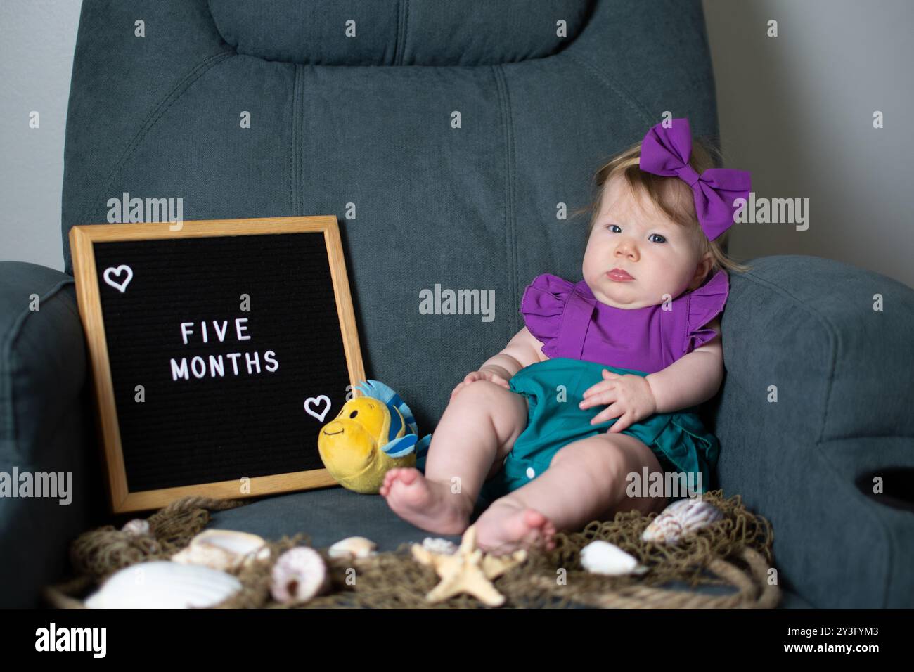 Jolie petite fille caucasienne dans un costume de sirène. bébé de 5 mois avec un tableau à lettres en feutre célébrant un mini anniversaire. Photo-shoot ide mensuel de photos de bébé Banque D'Images