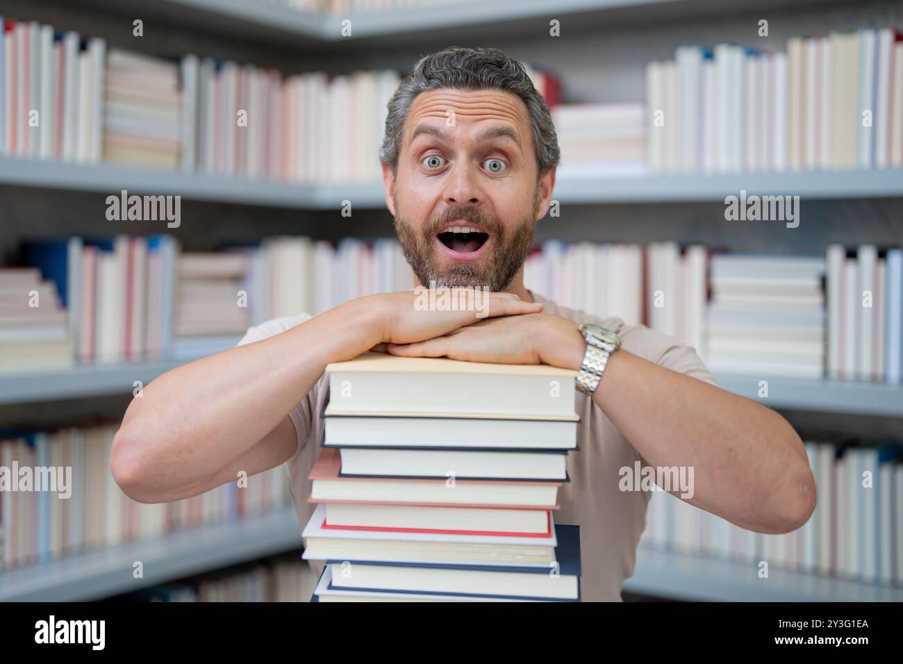 Drôle d'enseignant de tenir beaucoup de livres. Professeur fou avec des livres. Enseignant enthousiaste dans la bibliothèque de livres de l'école. Examen universitaire. Étudier enseigner à l'université. Éducateur Banque D'Images