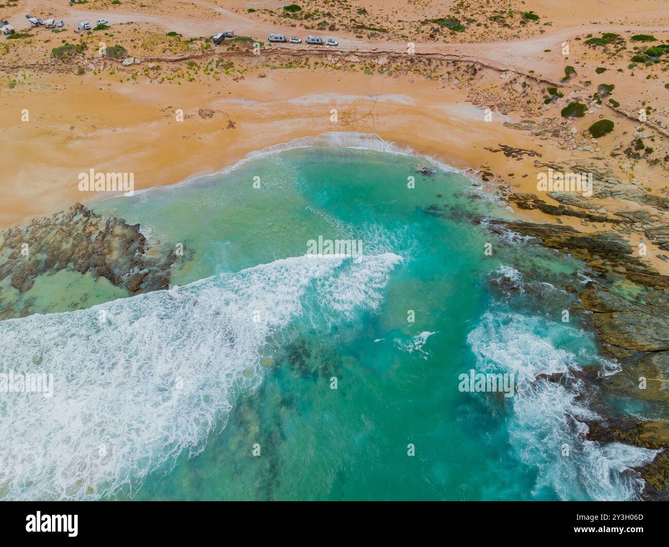 Vue aérienne des vagues se brisant dans une petite baie avec des caravanes garées à un belvédère au-dessus de Greenley Beach sur la péninsule d'Eyre en Australie méridionale Banque D'Images