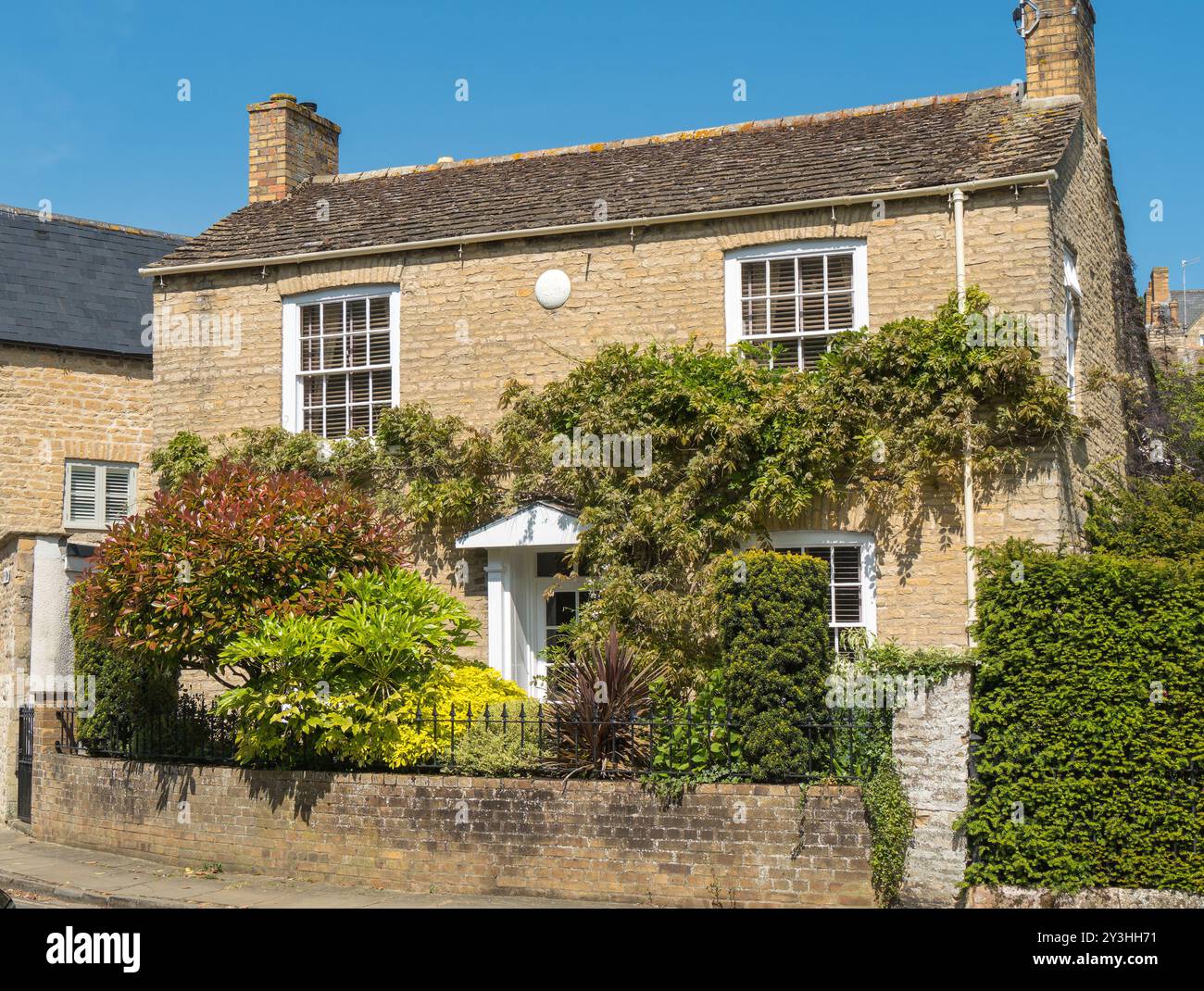 Attrayant, ancienne (c 1826) maison de chalet en pierre avec wisteria d'escalade, fenêtres à guillotine géorgiennes et balustrades métalliques, Bath Row, Stamford, Angleterre, Royaume-Uni Banque D'Images