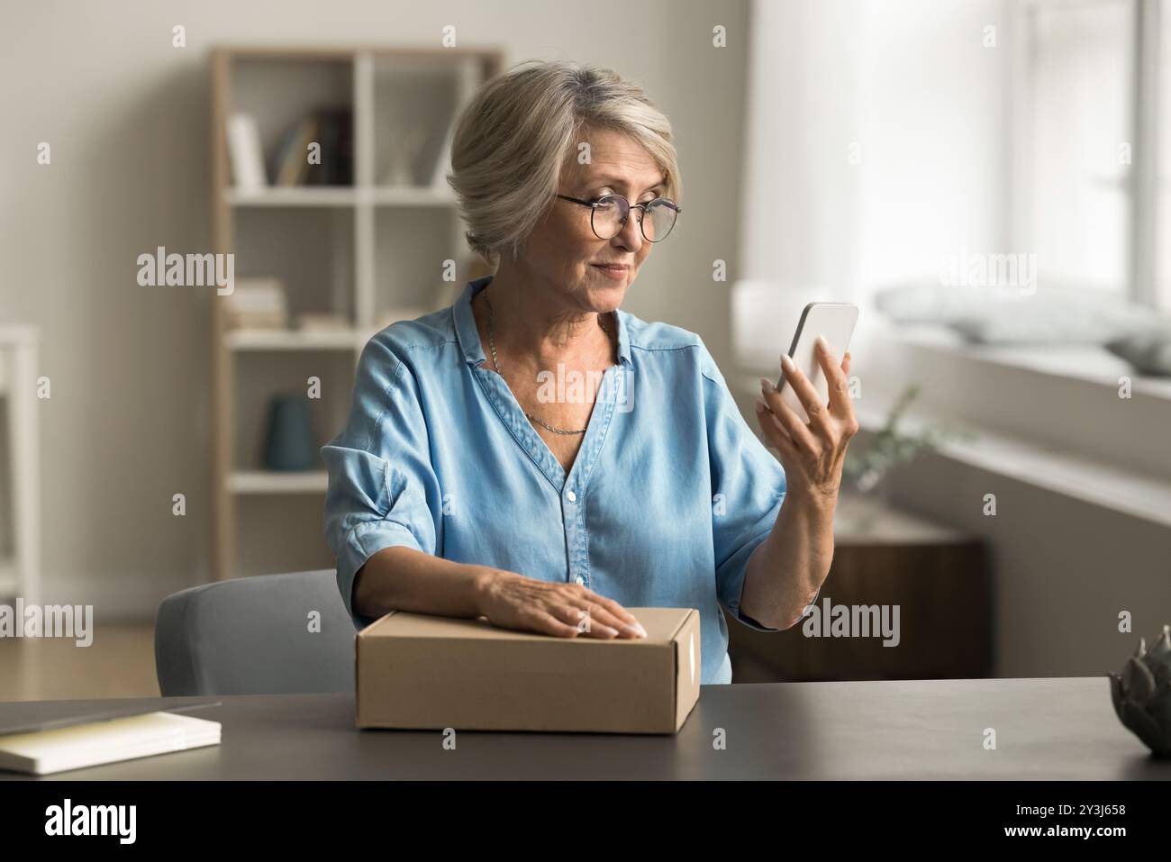 Femme appelle un coursier pour ramasser un colis préparé Banque D'Images