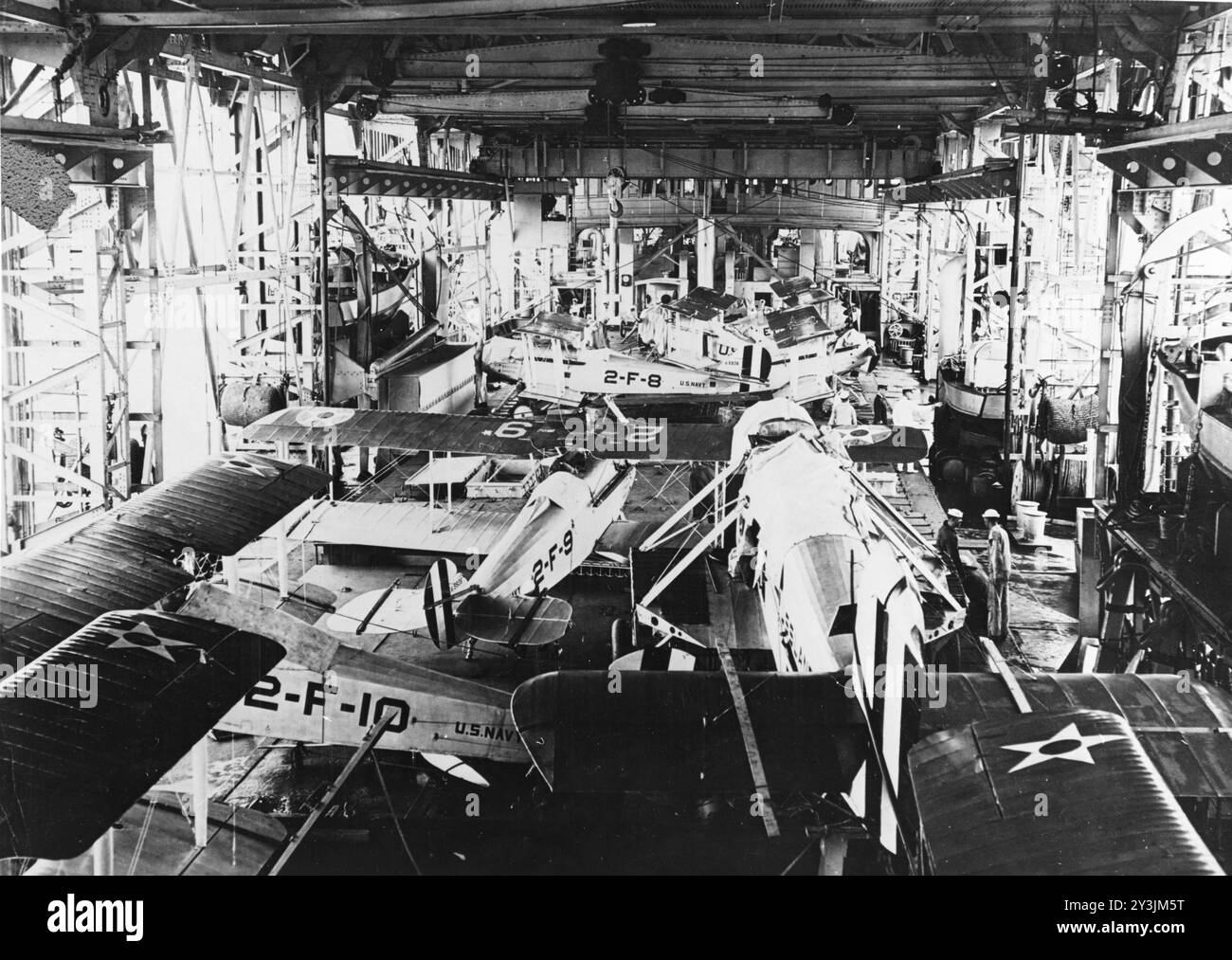 Vue du hangar du premier porte-avions USS Langley (CV-1) de la Marine des États-Unis dans les années 1920 Le plus grand avion au premier plan est un bombardier-torpilleur Douglas DT, avec ses ailes enlevées. D'autres avions sont des Vought VE-7 du Fighter Squadron 2 (VF-2), y compris les Bunos A5936 (marqué '2-F-9') et A5938 (marqué '2-F-8'). Les bateaux du navire sont arrimés le long des côtés du hangar. Photo de l'US Navy. Banque D'Images