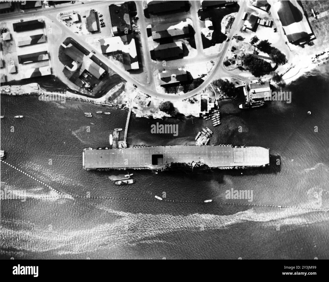 Le porte-avions USS Enterprise (CV-6) est amarré à Ford Island, Pearl Harbor, Hawaï, le 12 juillet 1942. Notez le Grumman F4F Wildcat sur la barge à l'arrière à côté, ainsi que les filets anti-torpilles et les bâtiments camouflés sur Ford Island. Photo de l'US Navy. Banque D'Images