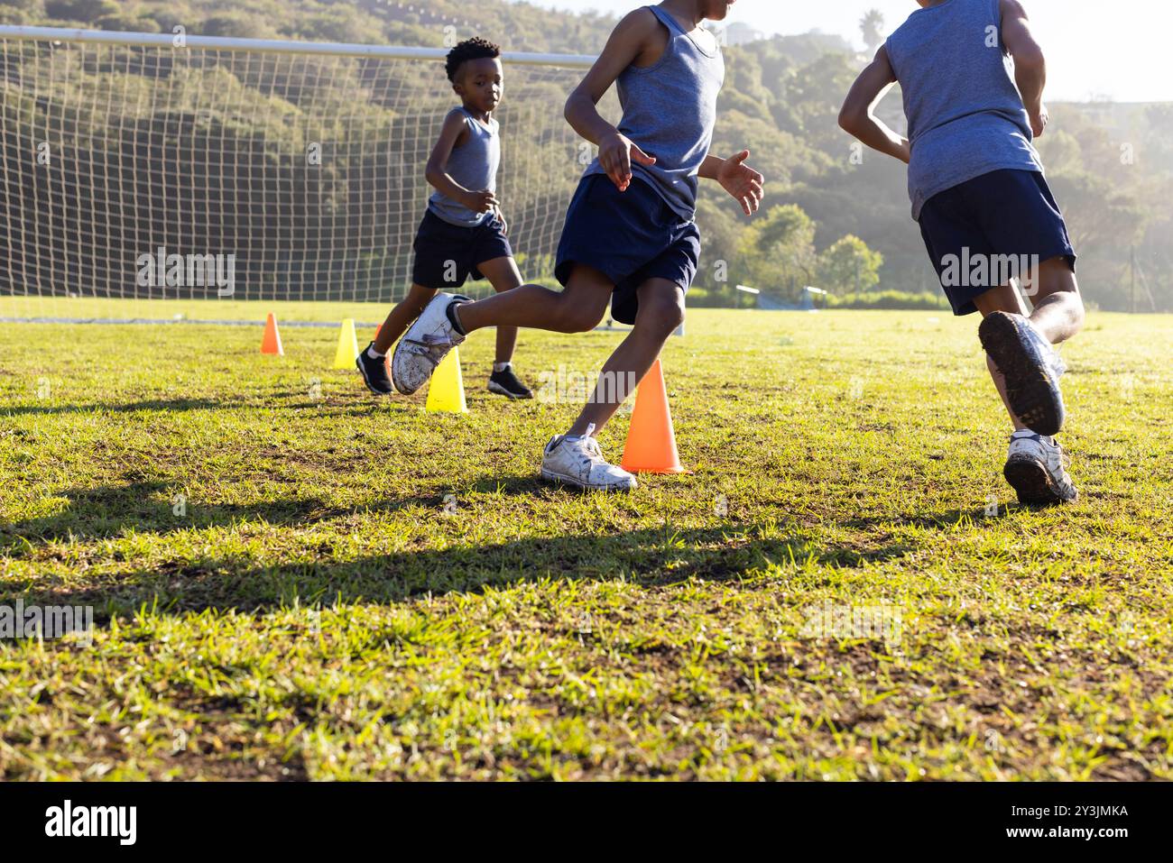 Courir autour de cônes sur le terrain d'école, garçons multiraciaux participant à des activités sportives de plein air Banque D'Images