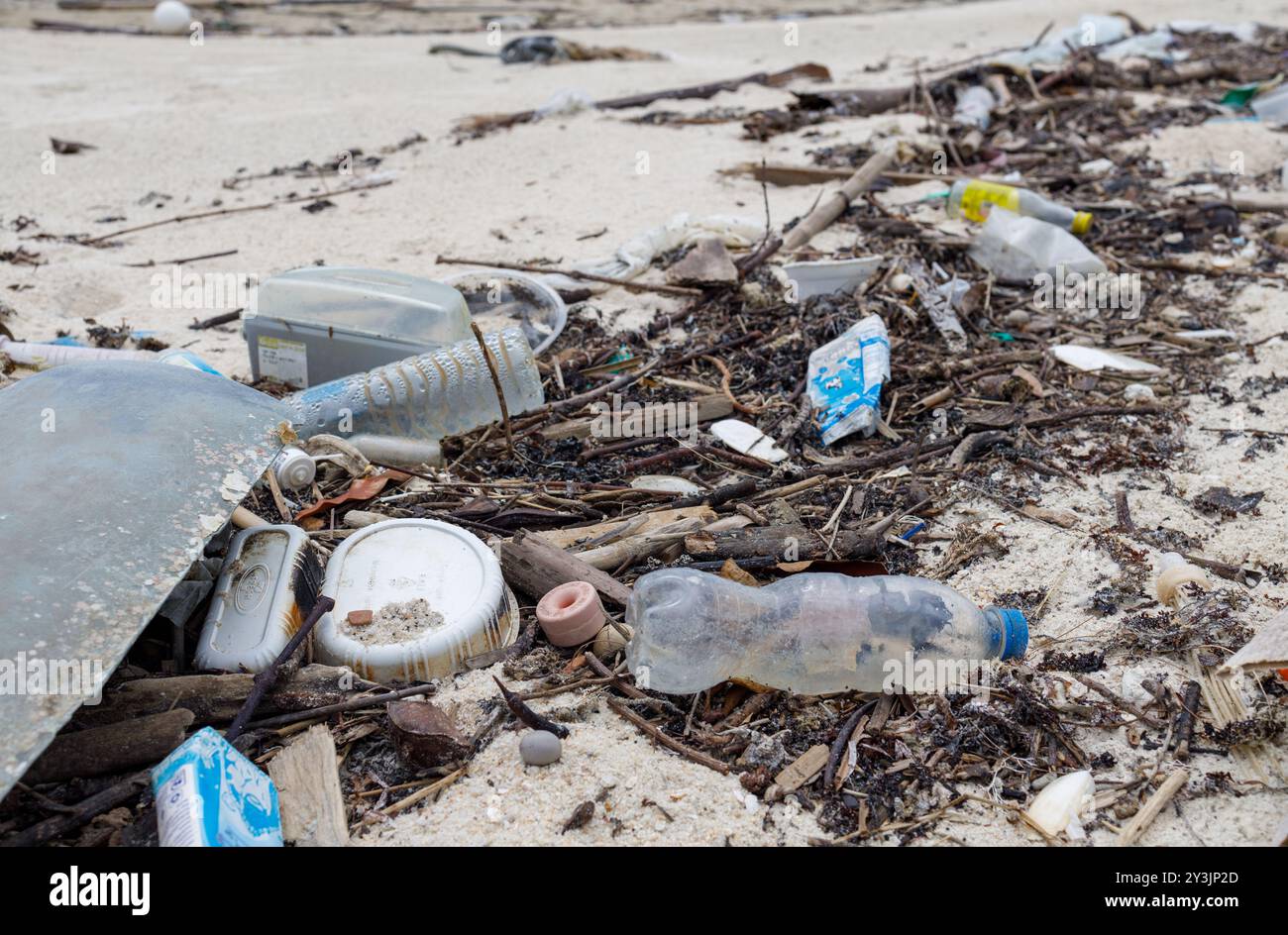 Une plage polluée sur Ko Samui, en Thaïlande, jonchée de bouteilles en plastique, de contenants alimentaires et de divers types de débris. Cette image met en évidence l'environnement Banque D'Images