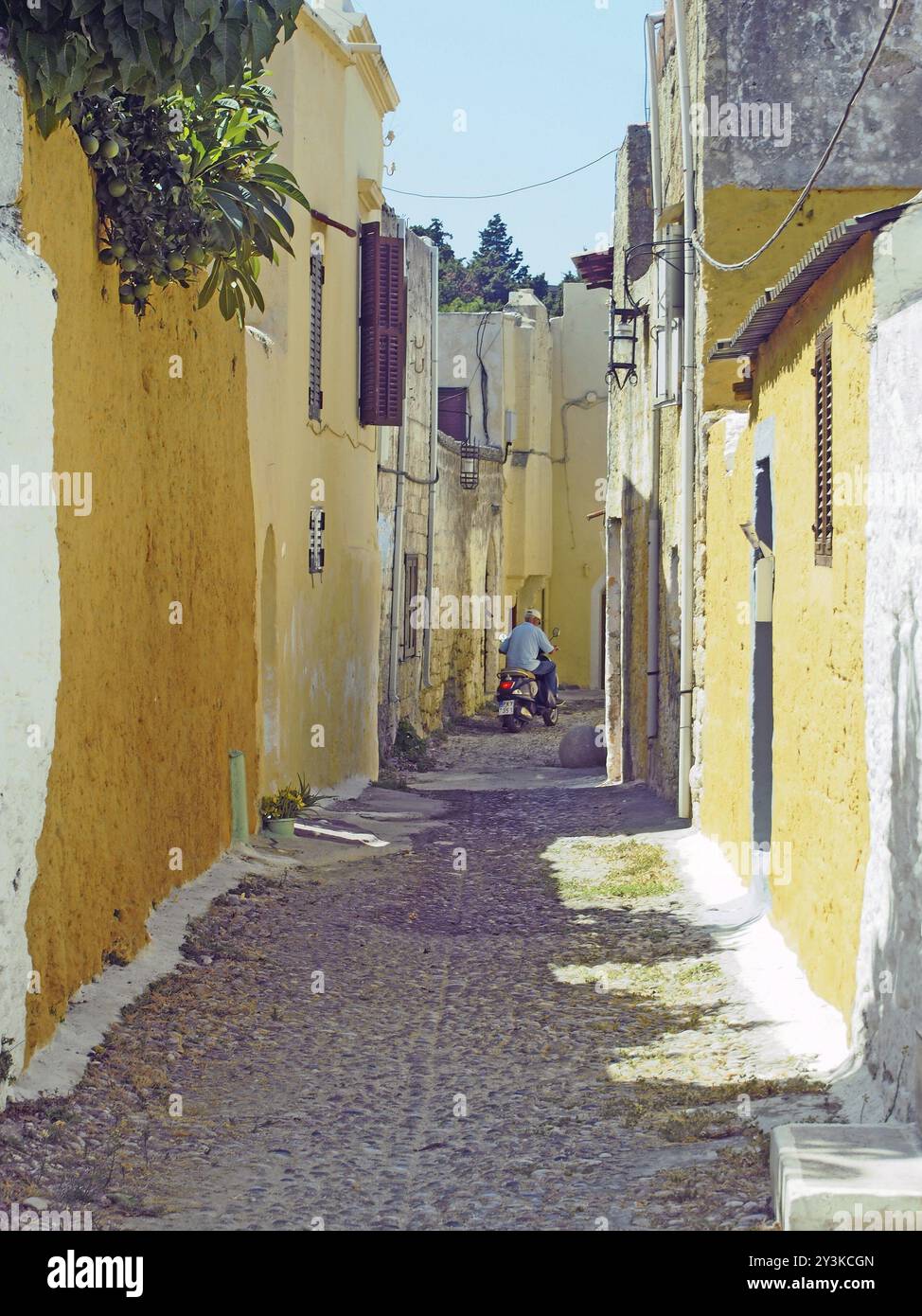 Rhodes Town, rhodes, grèce, 07 septembre 2017 : un homme conduisant un scooter le long d'une étroite ruelle de maisons traditionnelles dans la ville de rhodes Banque D'Images