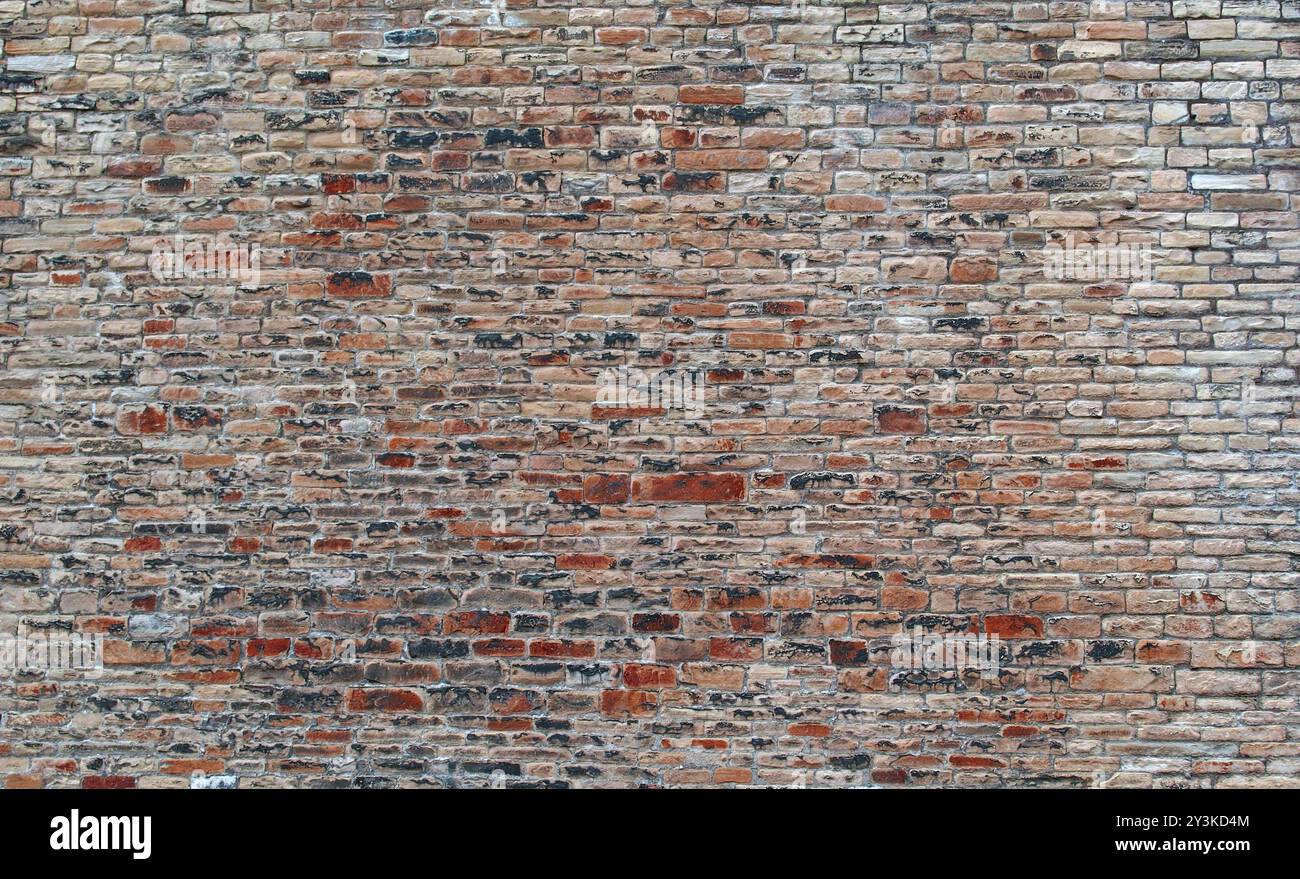 Mur en pierre extérieur rouge avec de nombreuses briques rugueuses inégales et une surface texturée Banque D'Images