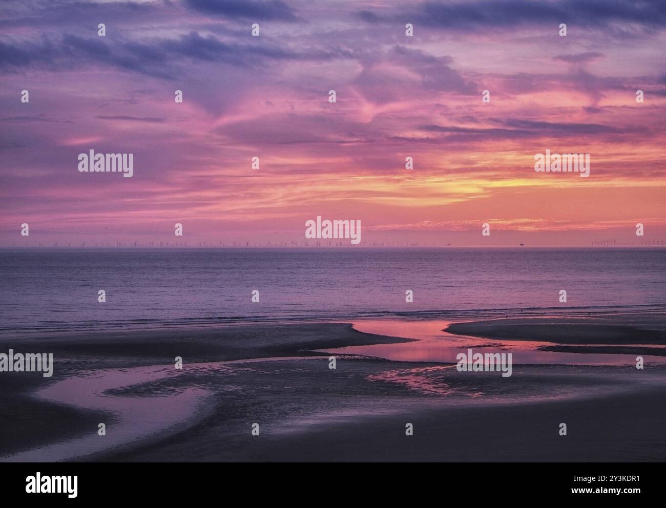 Belle près du crépuscule sombre sur une mer plate calme avec un ciel violet et des nuages bleus reflétés dans l'eau sur la plage Banque D'Images