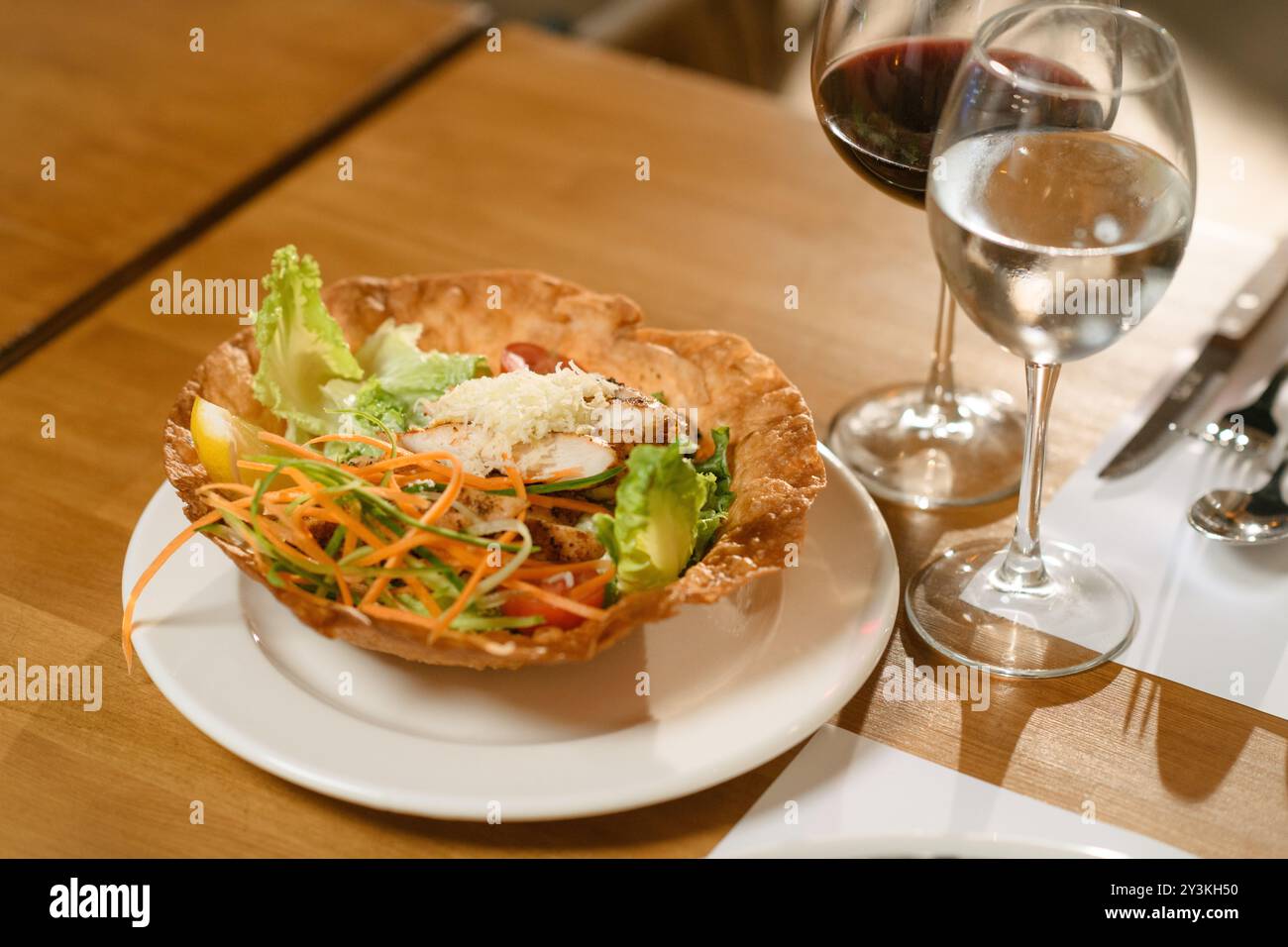 Salade fraîche du jardin garnie de tranches de poulet grillé, de fromage râpé et de légumes frais dans un bol à tortilla croustillant. Une option saine et vibrante Banque D'Images