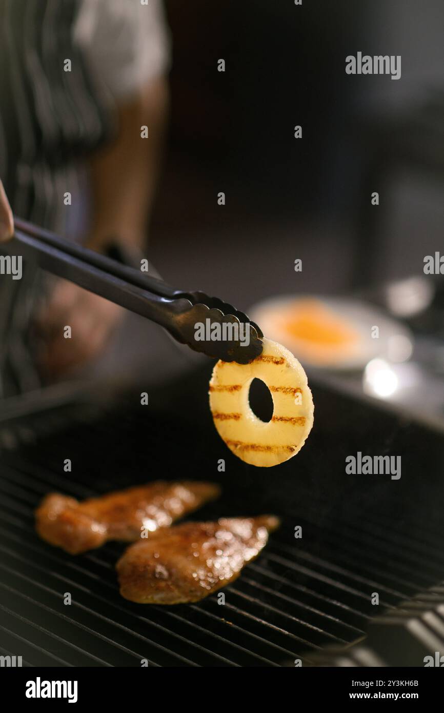 Filets de poulet tendres et anneau d'ananas grésillant sur un gril chaud, parfaitement assaisonnés pour une combinaison salée-sucrée dans la cuisine de l'hôtel Banque D'Images