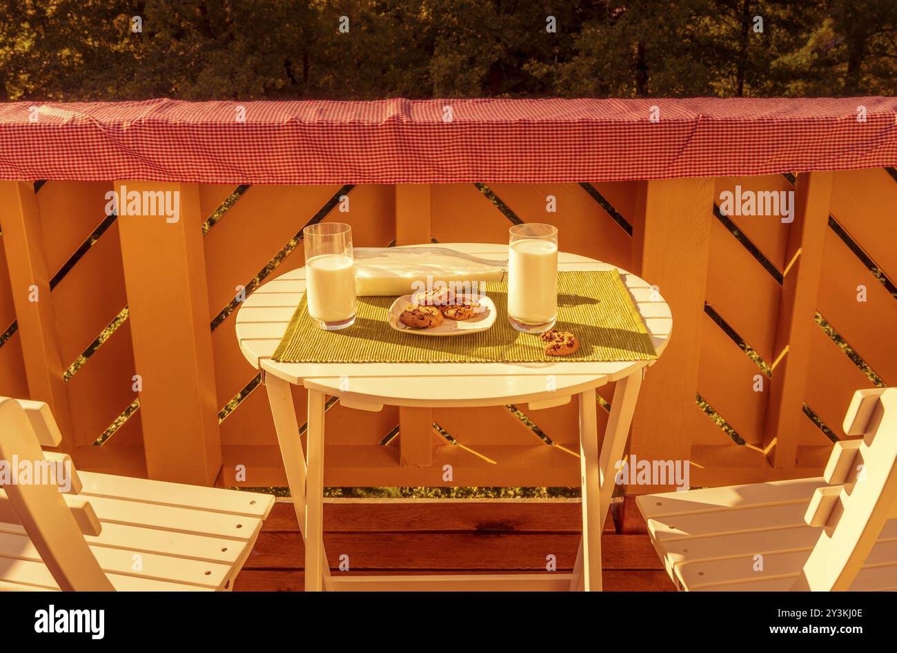 Joyeuse photographie culinaire avec petit déjeuner, biscuits et verres de lait, servi sur un balcon sur une petite table blanche Banque D'Images