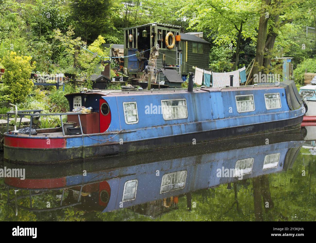 Un vieux bateau bleu et étroit amarré à côté de hangars en bois avec lavage sur la ligne sur le canal rochdale près du pont hebden Banque D'Images