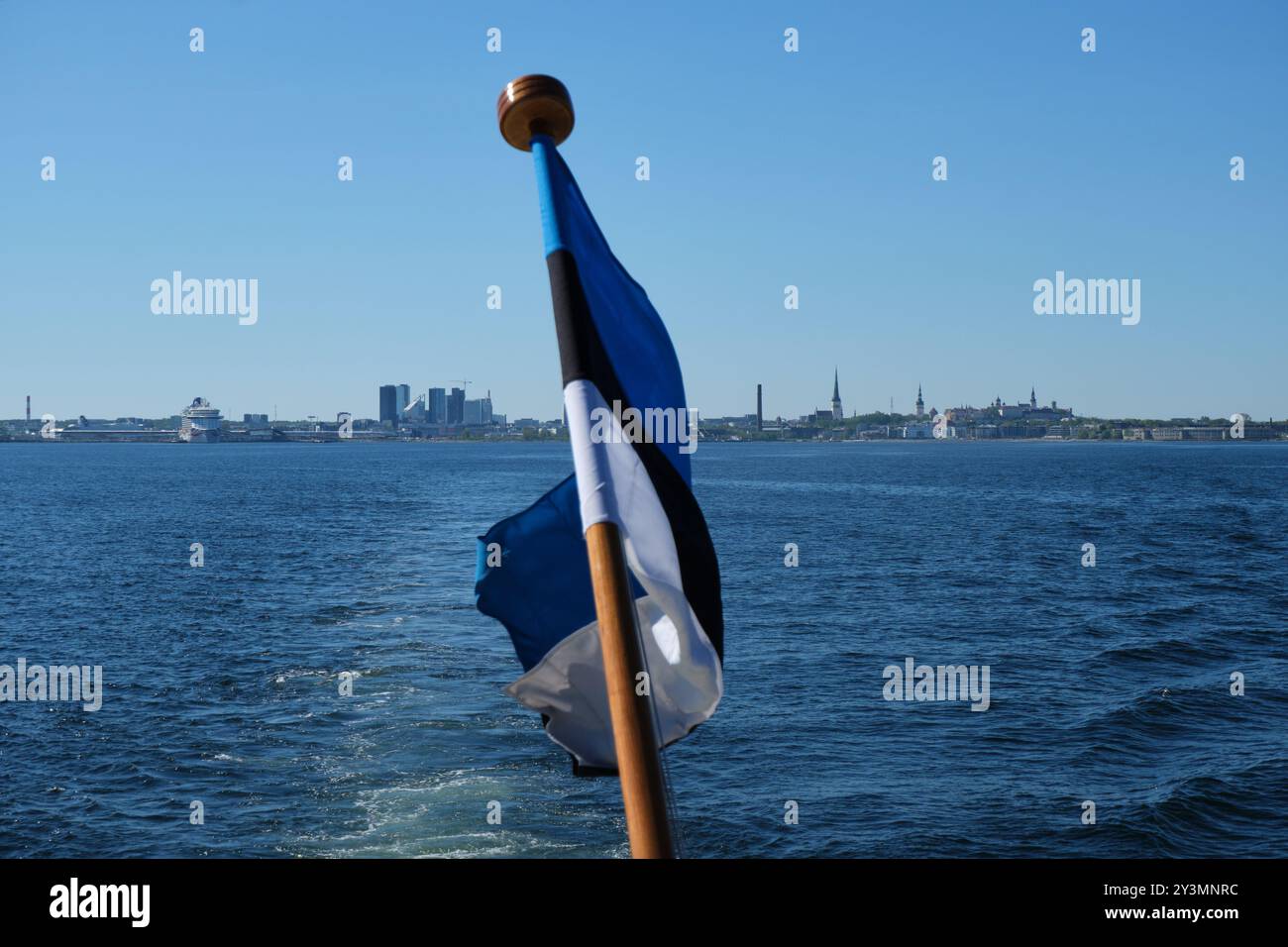 Drapeau estonien agitant devant le port de Tallinn, la vieille ville, la skyline et la mer Baltique, vu du bateau. La ville en vedette. Banque D'Images