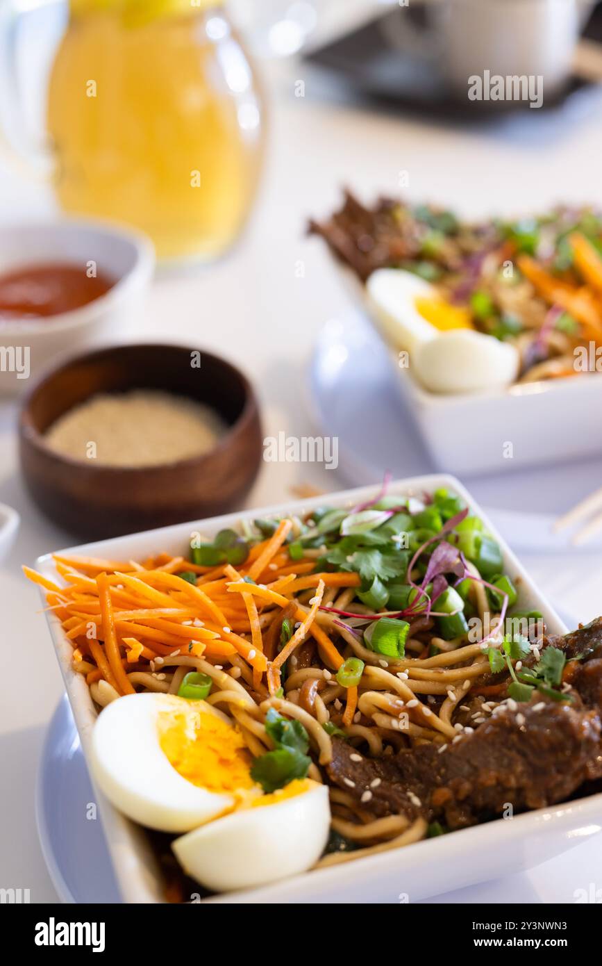 À la maison, gros plan d'un délicieux bol ramen avec oeuf dur, légumes et lanières de bœuf Banque D'Images