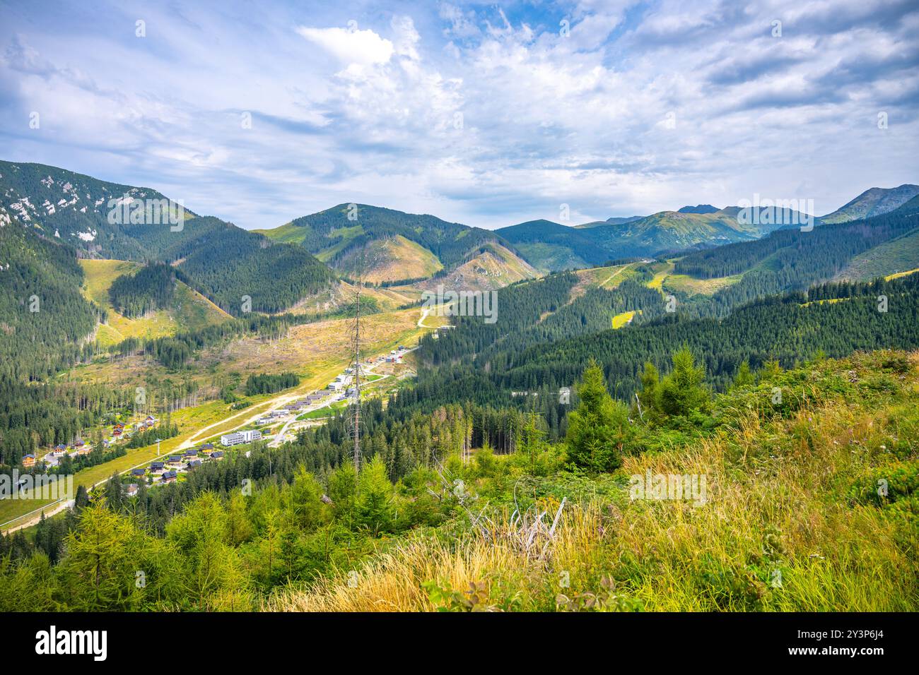 Une vue panoramique capture la beauté de la station de montagne Jasna nichée sous la montagne Chopok dans les basses Tatras. Une végétation luxuriante et des pentes de montagne créent un paysage pittoresque par une journée lumineuse. Banque D'Images