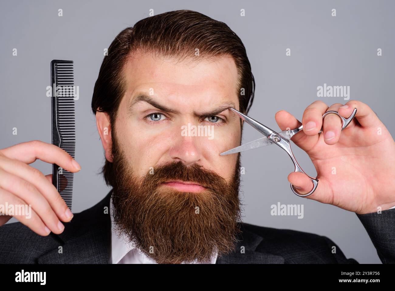 Homme barbu, homme barbu. Portrait de barbe homme élégant avec ciseaux de barbier et peigne de barbier dans le salon de coiffure. Client barbu visitant un salon de coiffure. Bear Banque D'Images