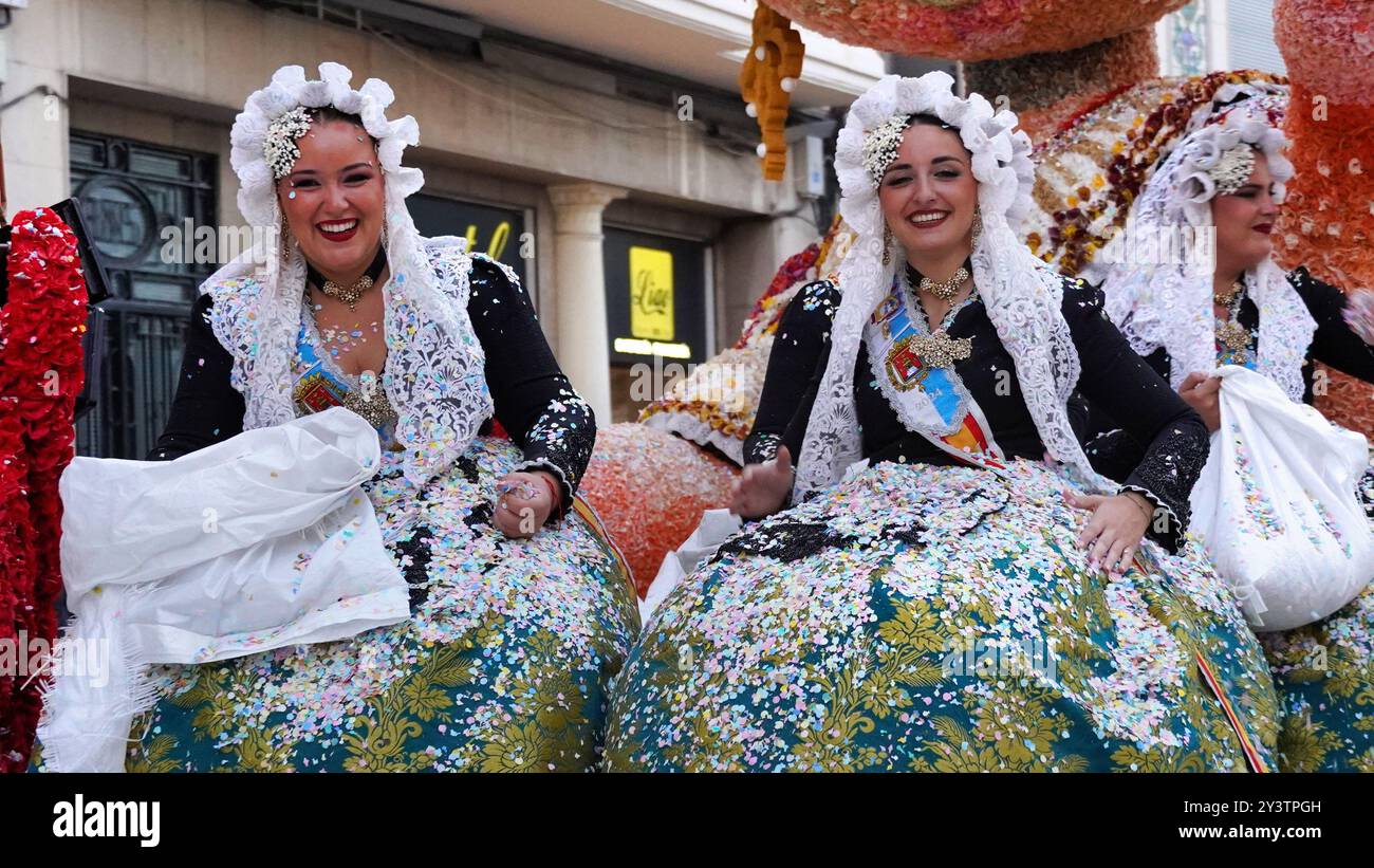 Femmes en robes espagnoles traditionnelles célébrant un défilé festif, couvertes de confettis colorés, incarnant la joie et le dynamisme de la culture locale. Banque D'Images