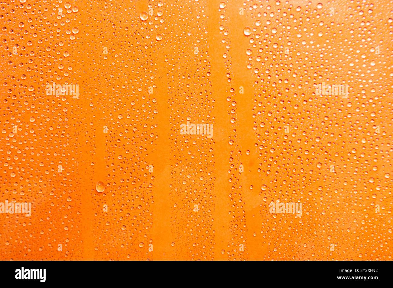 Gouttelettes d'eau sur fond de couverture orange. Banque D'Images