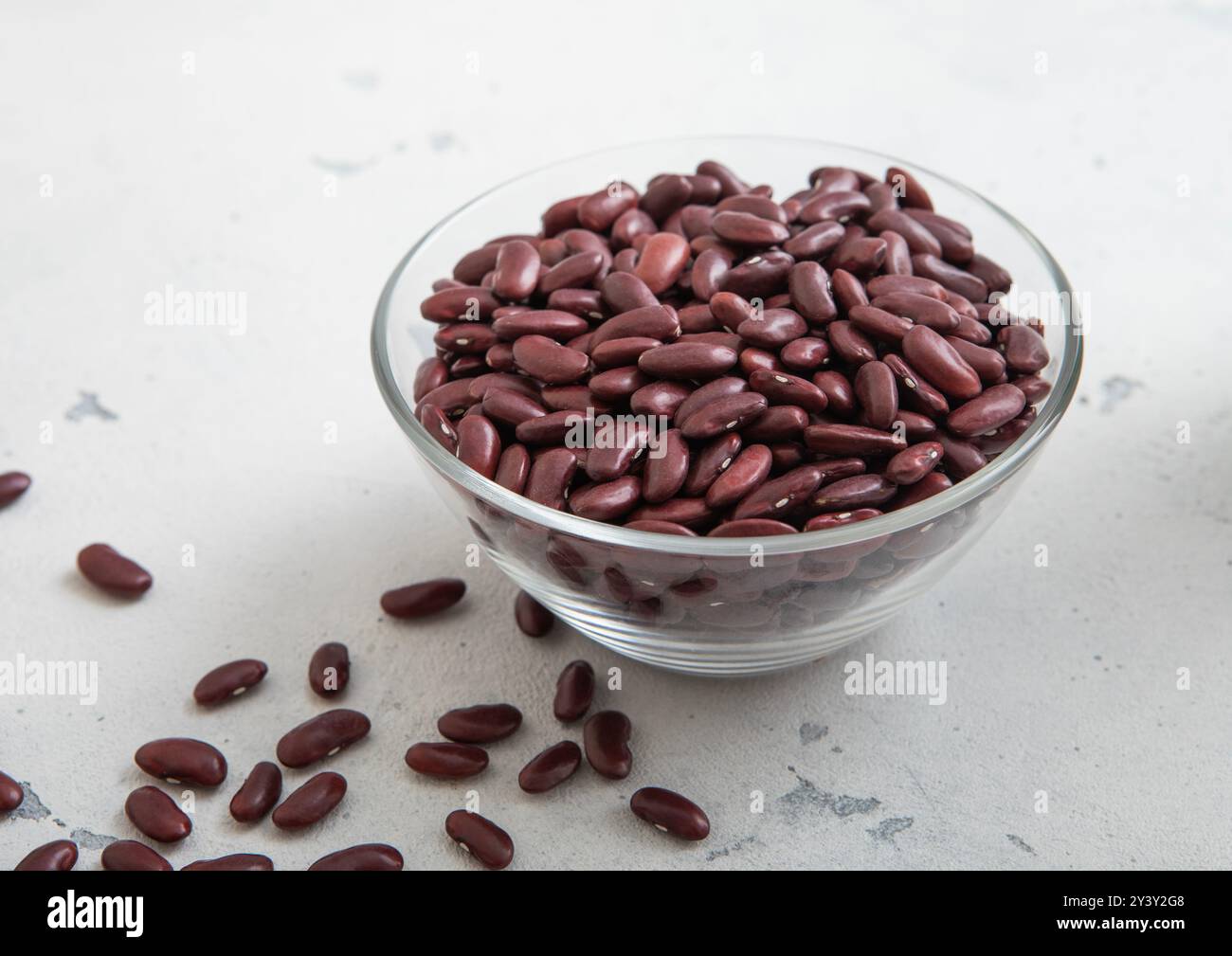 Séchez les haricots mauves biologiques crus dans un bol en verre sur une table lumineuse. Banque D'Images