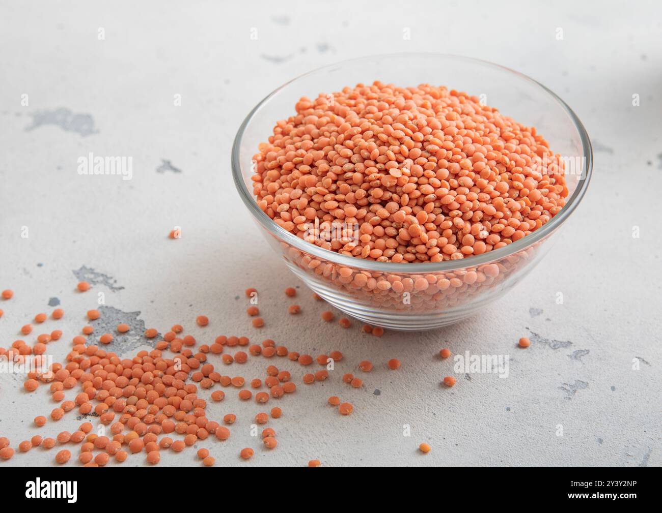 Séchez les graines de lentilles orange crues dans un bol en verre sur une table lumineuse. Banque D'Images