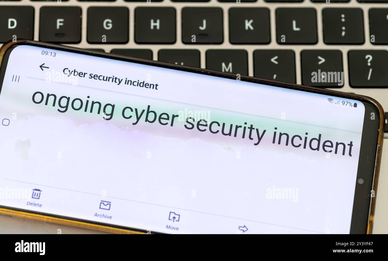 Gros plan sur un téléphone mobile d'une entreprise informant ses clients d'un incident de cybersécurité en cours. Banque D'Images