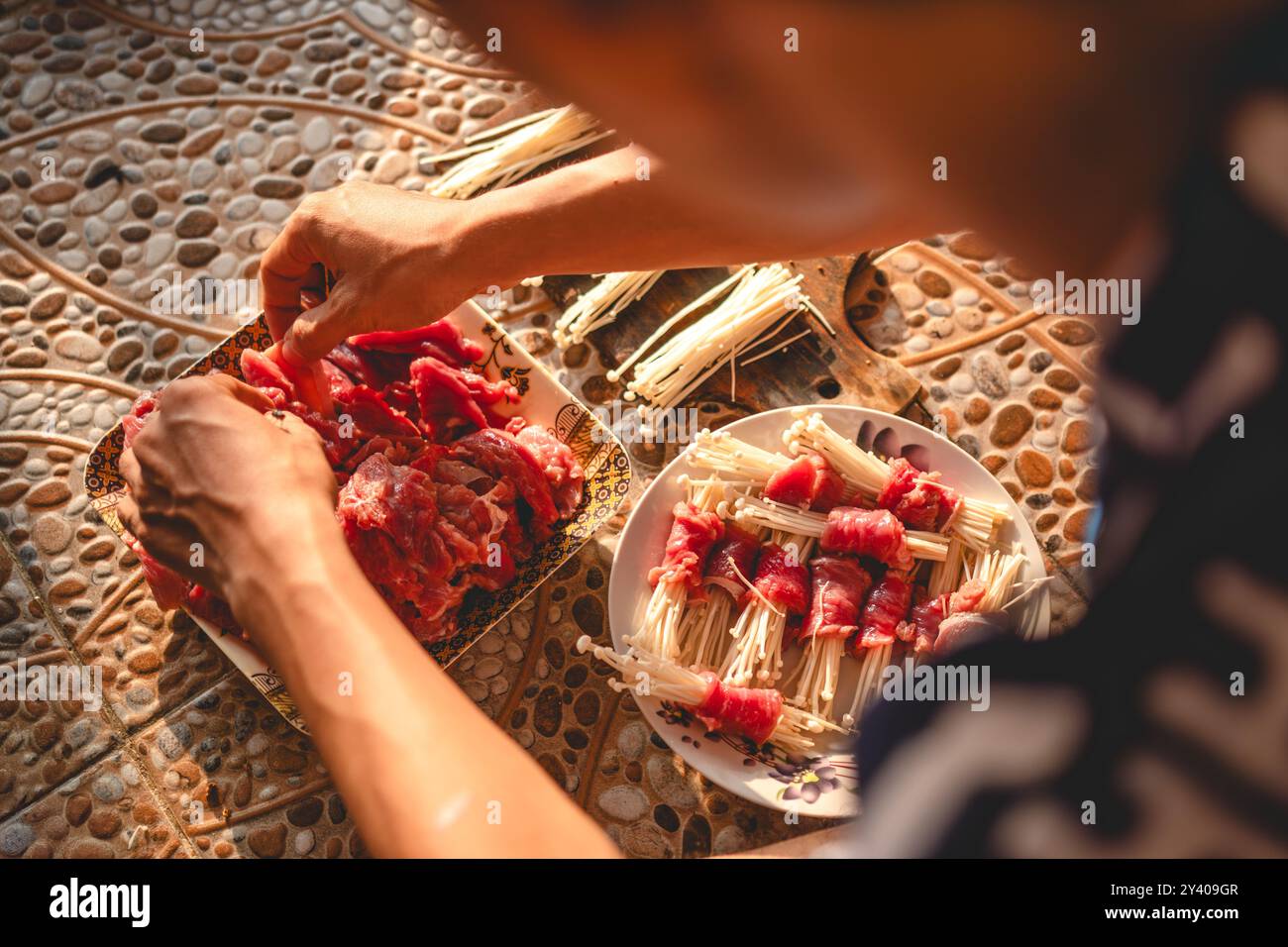 coupez les champignons enoki avec un couteau tranchant sur une planche à découper. couper les champignons parallèlement à la longueur de la viande préparée. photographiez à partir de la dsi droite Banque D'Images