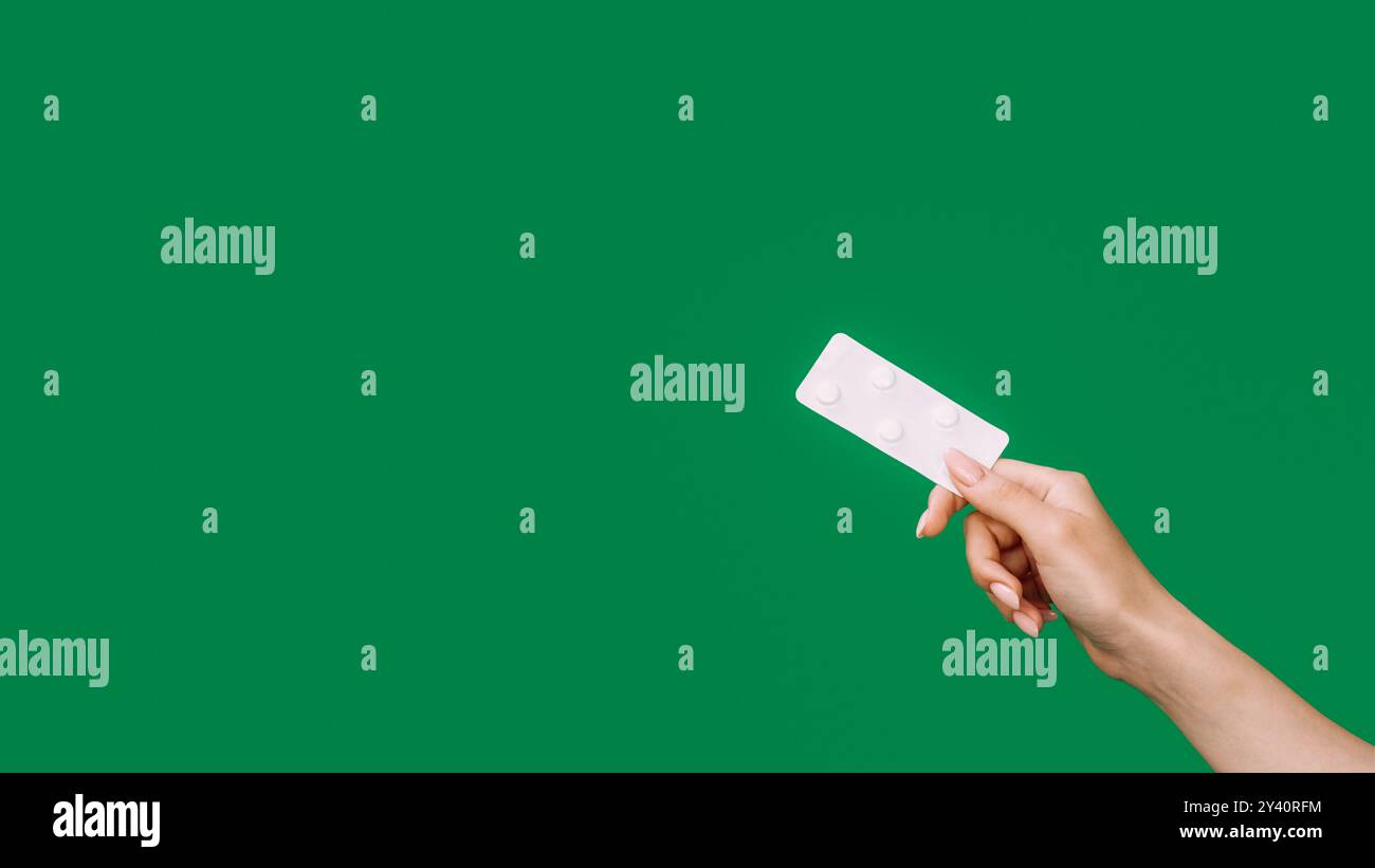 Médicaments sur ordonnance. Pilule. Industrie pharmaceutique. Main féminine offrant un blister antibiotique isolé sur fond vert d'espace vide. Banque D'Images