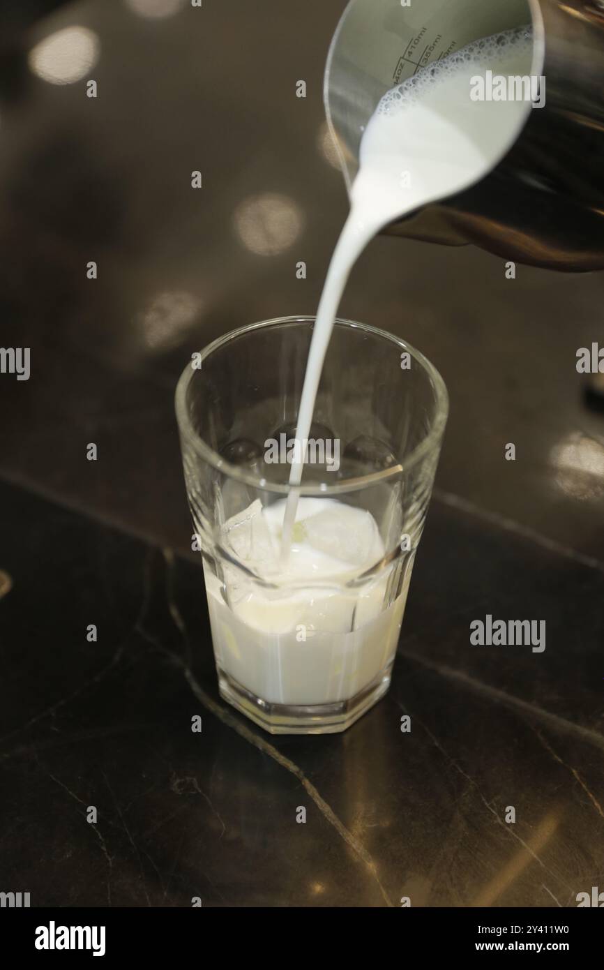 Lait froid versé dans un verre, prêt à compléter une dose d'espresso fraîche. Banque D'Images