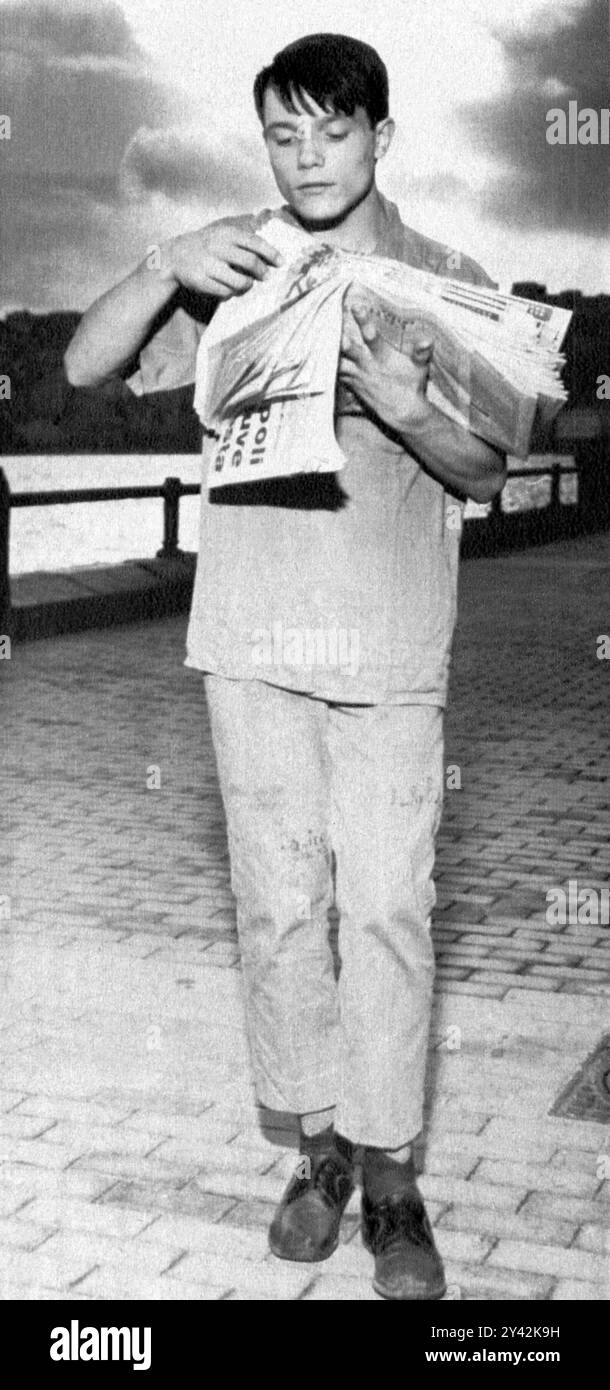 1965 , Naples , ITALIE : le célèbre chanteur et acteur pop italien MASSIMO RANIERI ( né Giovanni Calone , né le 3 mai 1951 ) âgé de 14 ans . Dans une photo publicitaire, il se présente comme un marchand de journaux ( Newsboy ou newsie ), un vendeur de rue de journaux sans kiosque fixe, une profession qu'il exerçait à cette époque pendant la journée et le soir il chantait dans des lieux publics, des restaurants, des déjeuners de mariage et des festivals populaires. Photographe inconnu . - STRILLONE - quotidiennement - giornali - journaux -STORICHE - PORTRAIT - RITRATTO - ITALIA - personalità da bambino bambini da giovane - Perso personnalité Banque D'Images