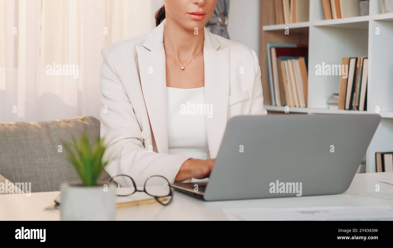 Travail du manager. Femme de bureau. Discussion virtuelle. Dame élégante méconnaissable en tapant le bureau assis d'ordinateur portable dans l'intérieur de la pièce lumineuse. Banque D'Images