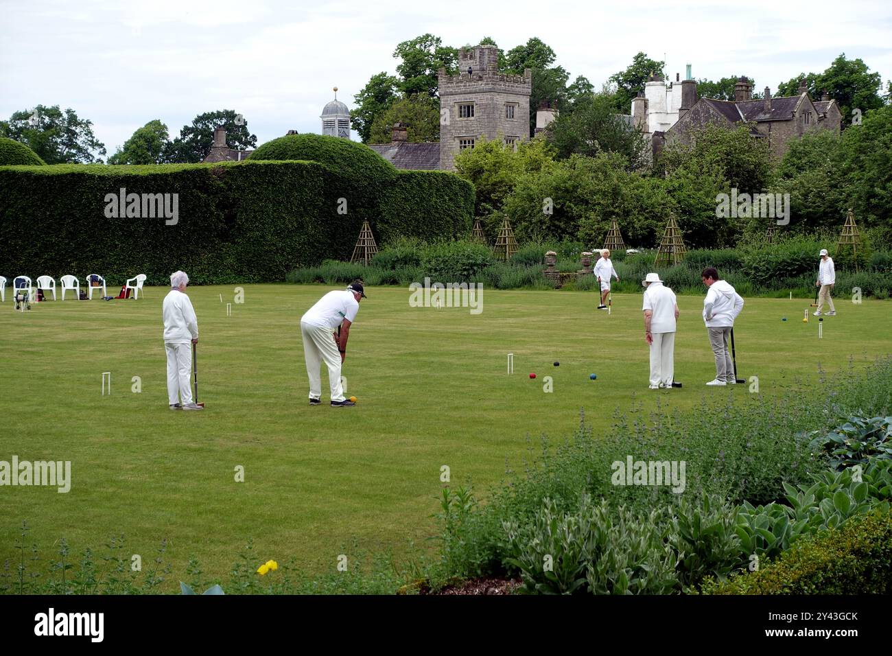 Personnes âgées jouant une partie de croquet sur la pelouse au Levens Hall Manor House Gardens dans le parc national du Lake District, Cumbria, Angleterre, Royaume-Uni. Banque D'Images