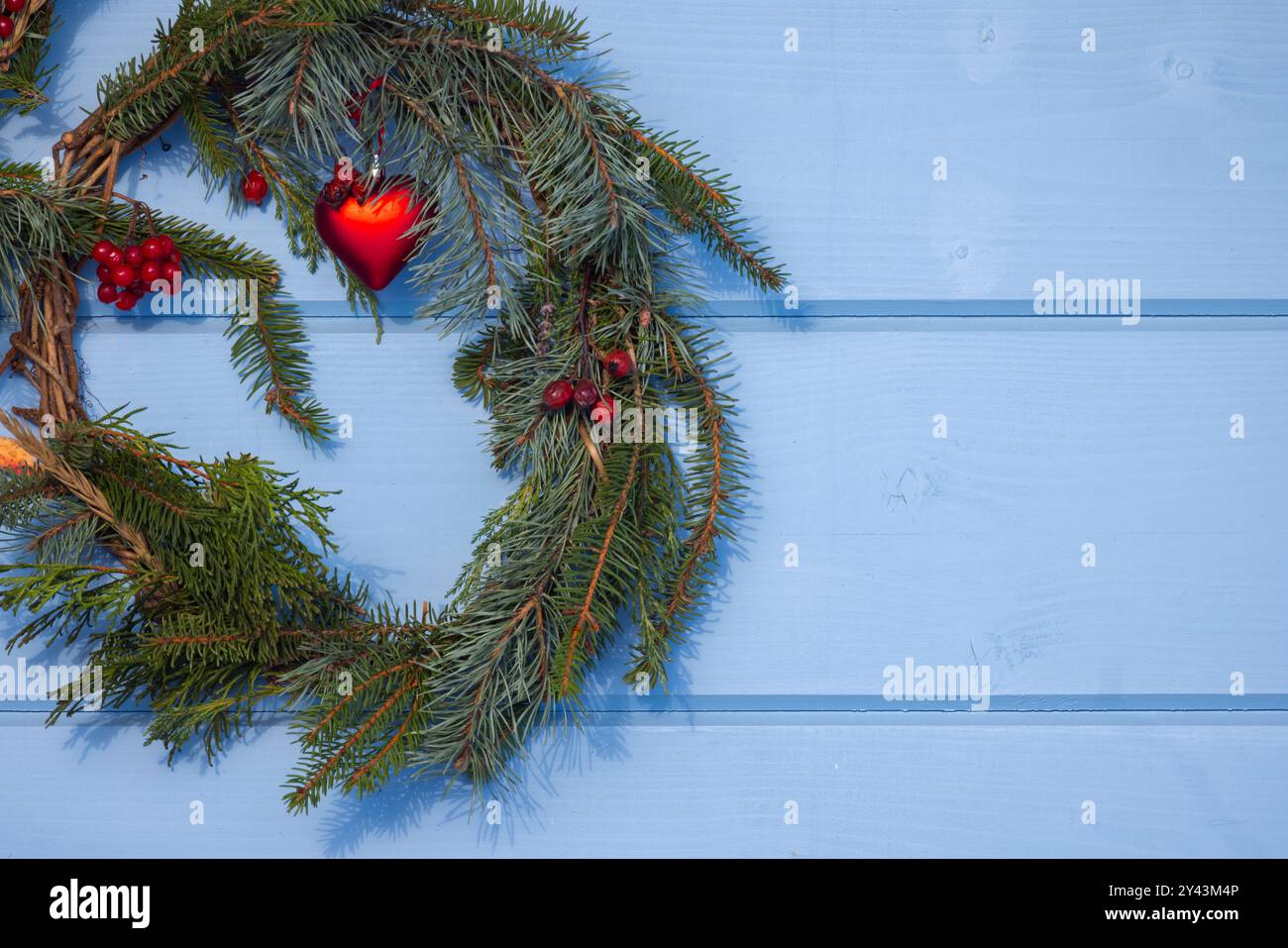 Couronne de Noël faite de branches d'épinette verte avec décoration accrochée sur un mur en bois bleu Banque D'Images