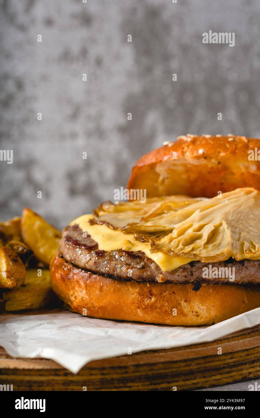 Hamburger avec des huîtres et du fromage cheddar sur une planche à découper en bois Banque D'Images