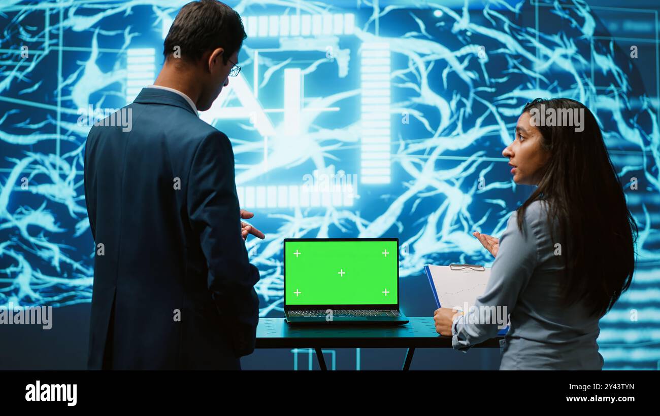 Des collègues de démarrage regardant des graphiques, en utilisant un logiciel d'IA sur un ordinateur portable maquette pour prendre des décisions basées sur les données. Collègues travaillant en équipe développant des solutions d'intelligence artificielle pour l'entreprise, caméra A. Banque D'Images