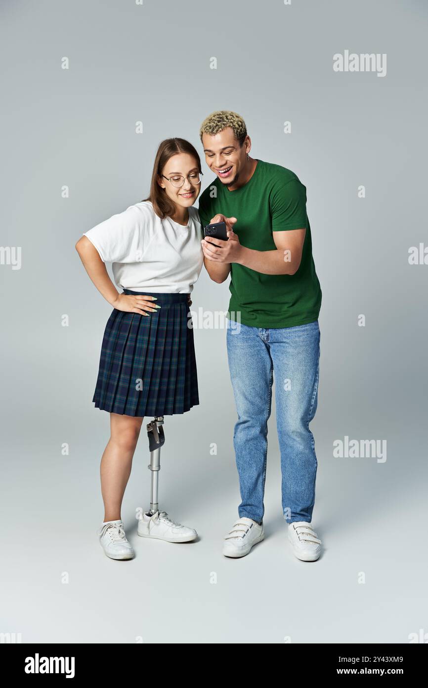Deux amis partagent la joie en regardant un appareil, l'un avec une jambe prothétique. Banque D'Images
