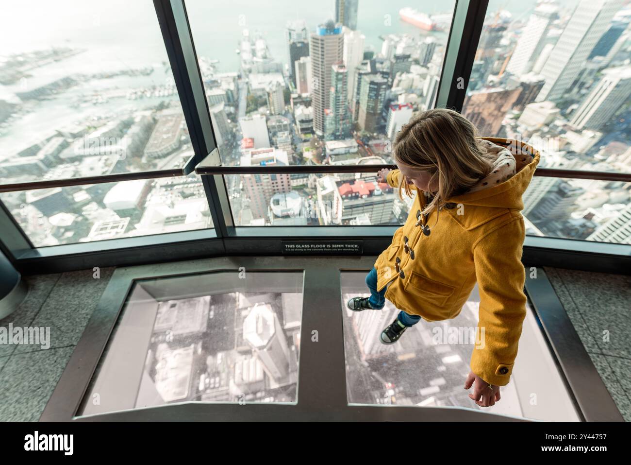 Fille marchant sur le plancher de verre au-dessus des bâtiments en Nouvelle-Zélande Banque D'Images