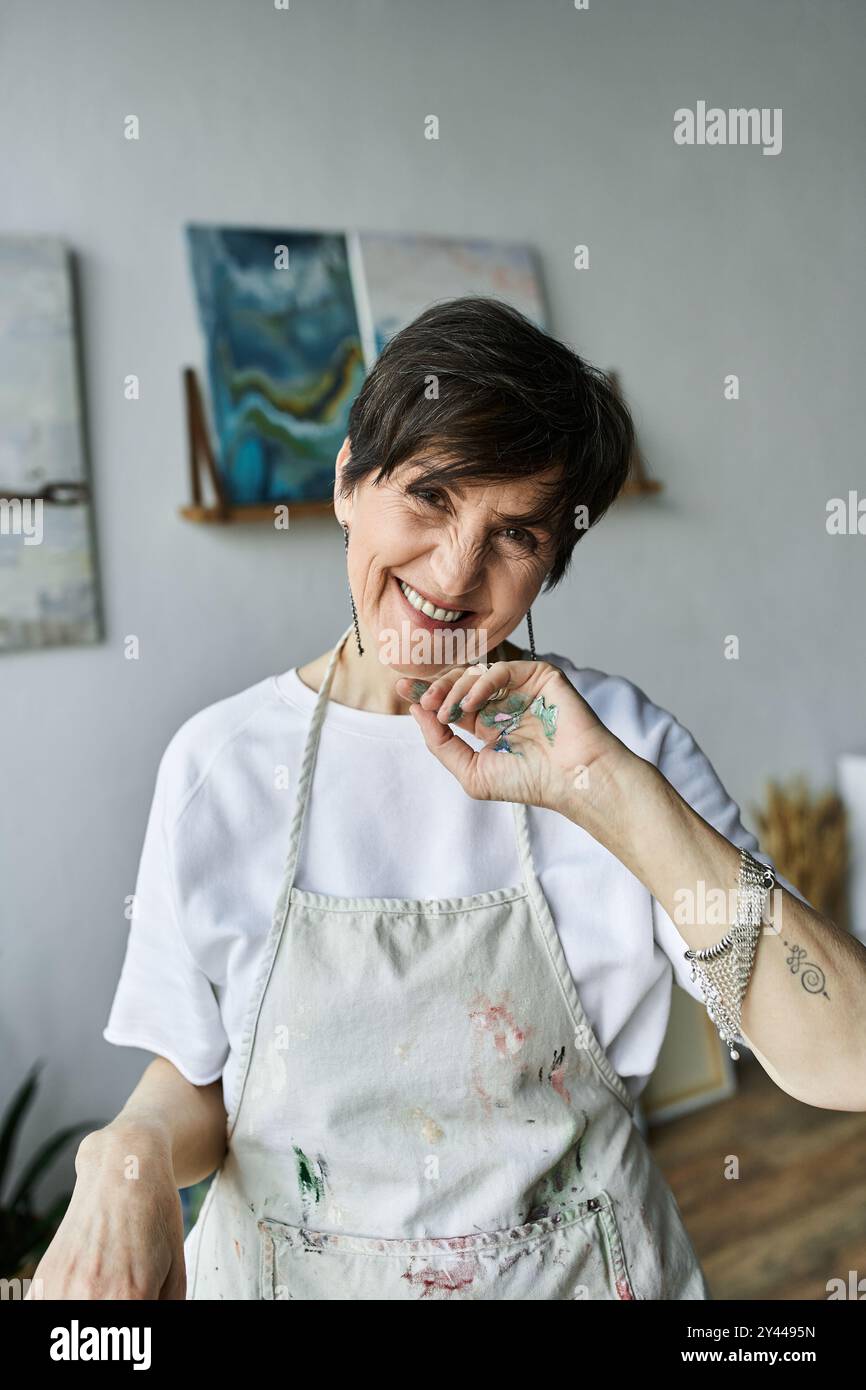 Femme mature rayonne de joie tout en créant de l'art dans son studio vibrant. Banque D'Images