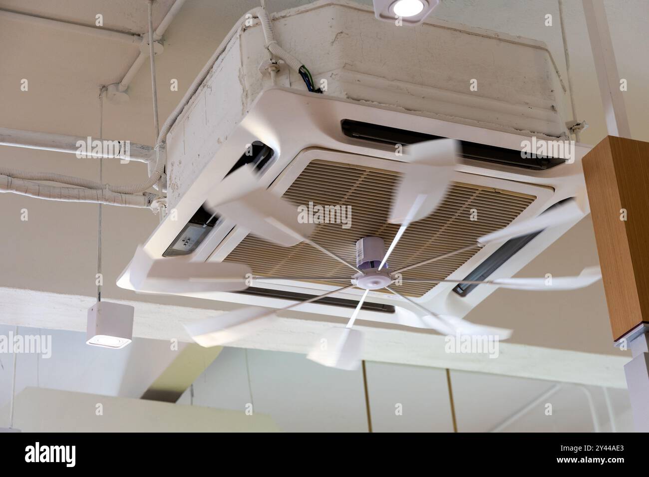 Volet de ventilateur rotatif fixé au climatiseur pour disperser l'air froid uniformément dans la pièce. Flou de mouvement du ventilateur prévu. Banque D'Images