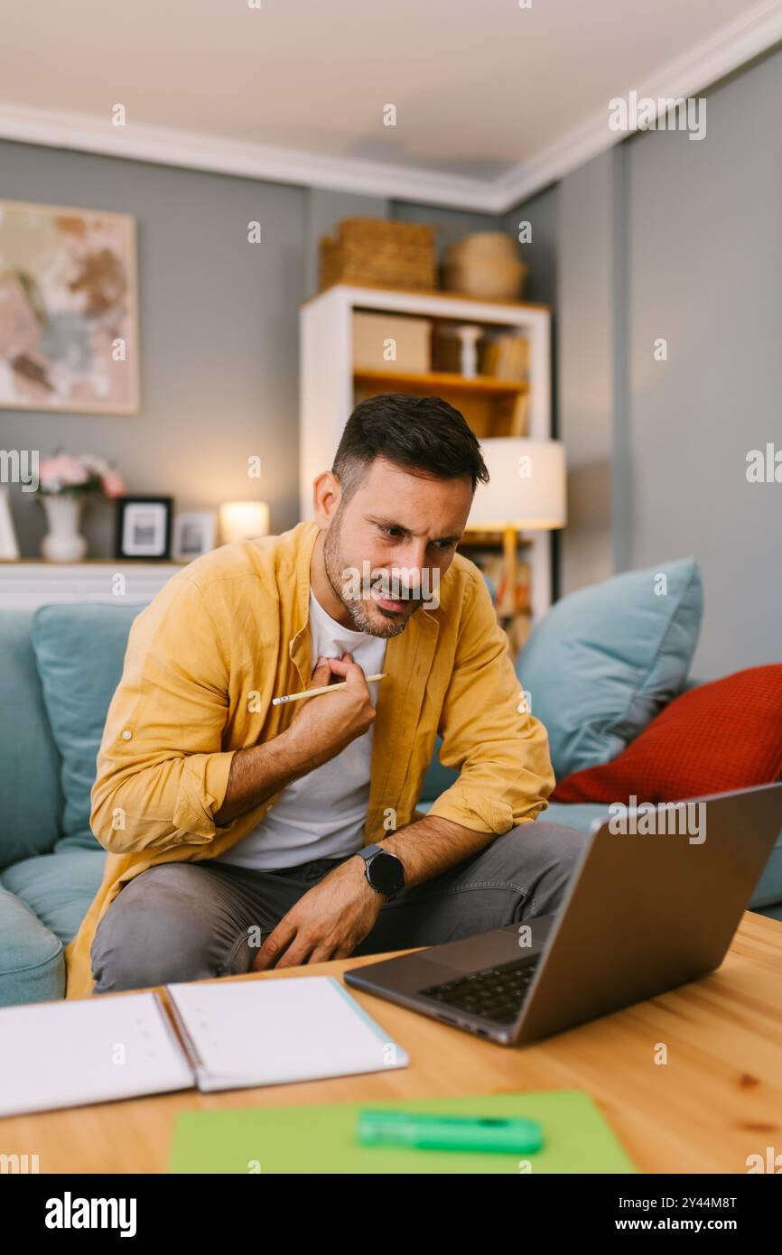 Homme frustré travaillant à la maison sur un ordinateur portable Banque D'Images