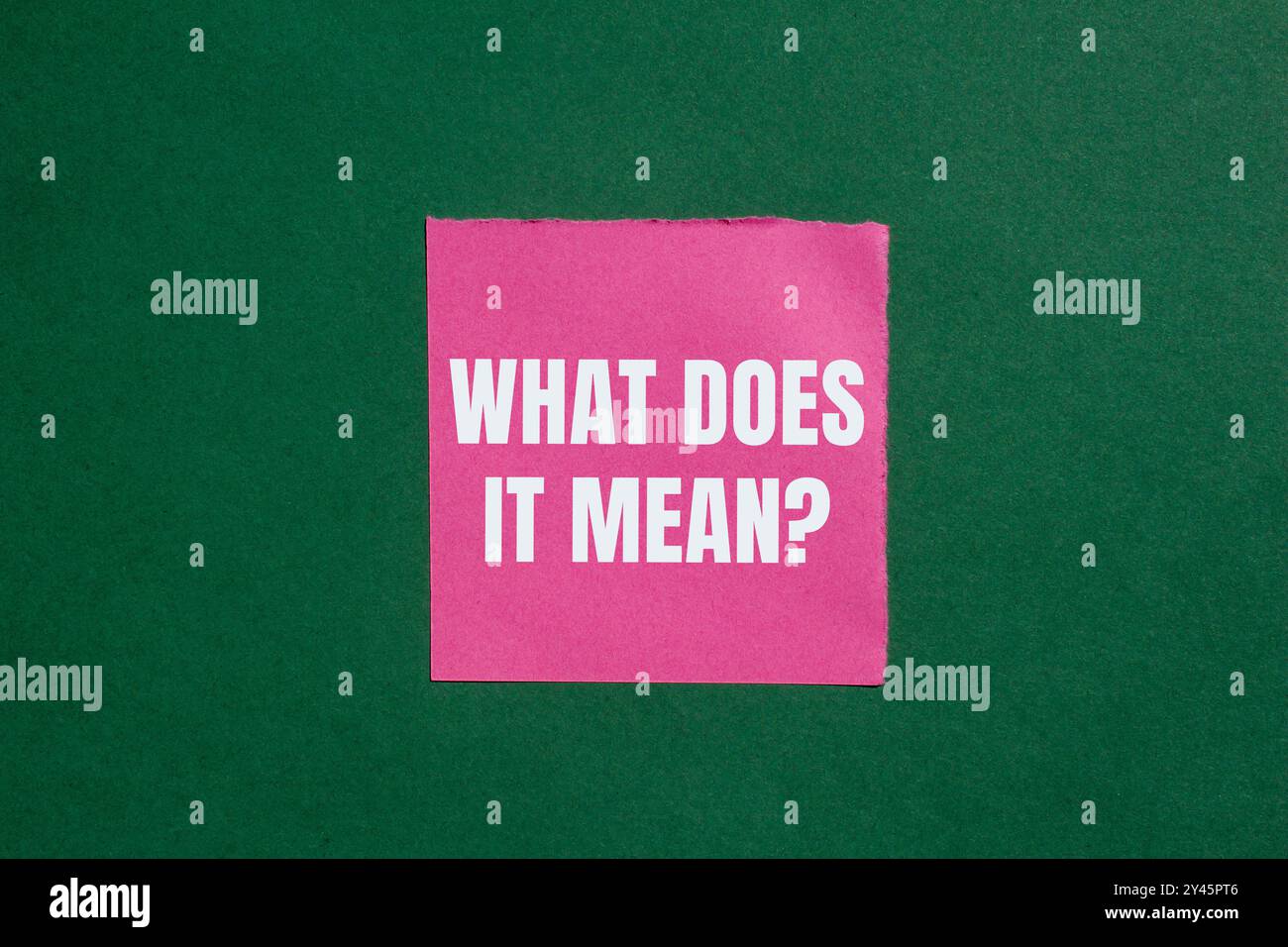 Qu'est-ce que cela signifie question écrite sur papier rose déchiré déchiré sur fond vert. Conceptuel qu'est-ce que cela signifie symbole de question. Copier l'espace. Banque D'Images